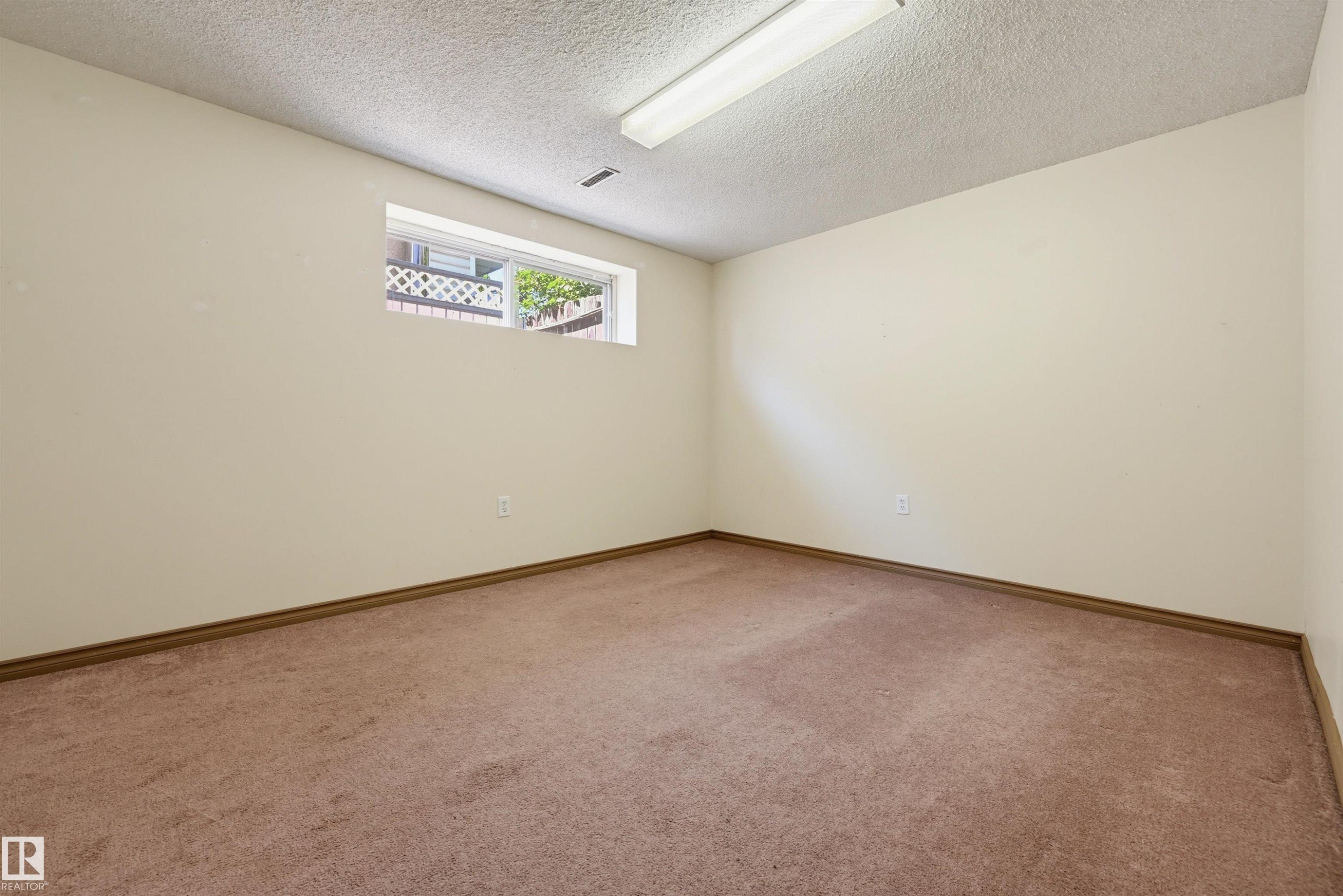 Recessed window opening, neutral wall paint, textured ceiling, flush-mount fluorescent lighting, and wall-to-wall carpeting - 6768 39 Avenue Nw, Edmonton, AB - Indoor Photo Showing Other Room