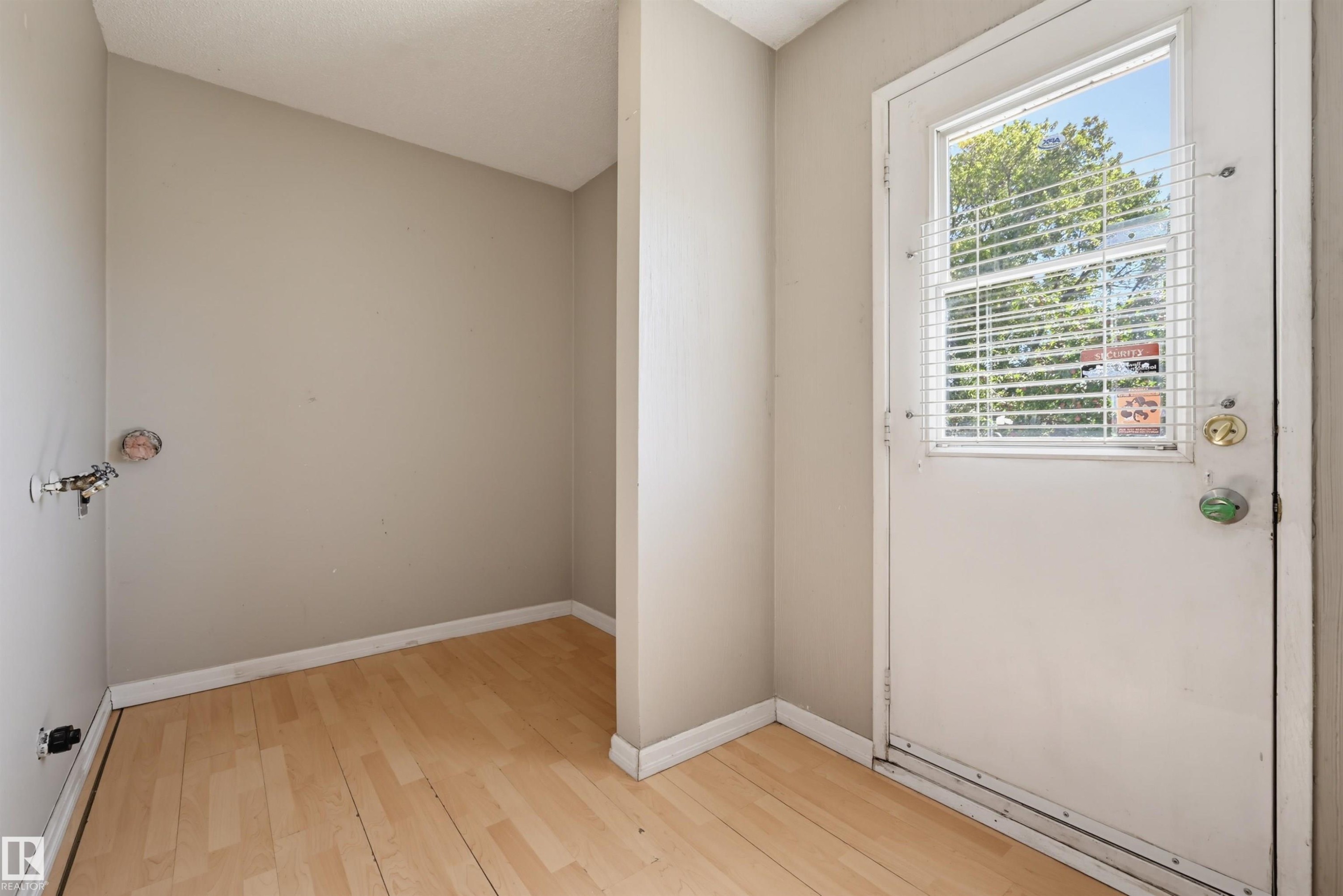 Wood-finish flooring with light-toned walls - 6768 39 Avenue Nw, Edmonton, AB - Indoor Photo Showing Other Room