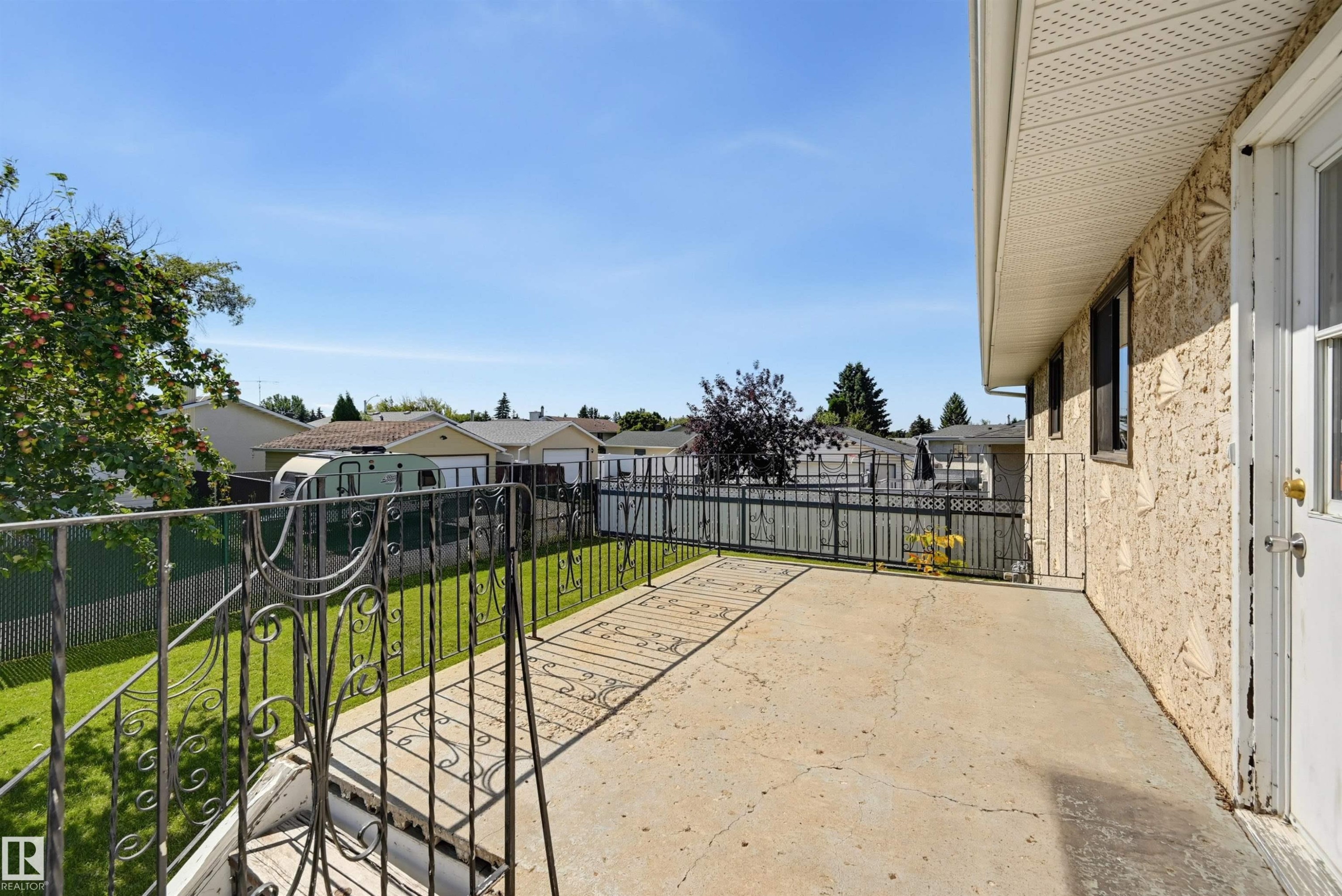 Spacious concrete patio with decorative wrought iron railing and stucco exterior - 6768 39 Avenue Nw, Edmonton, AB - Outdoor