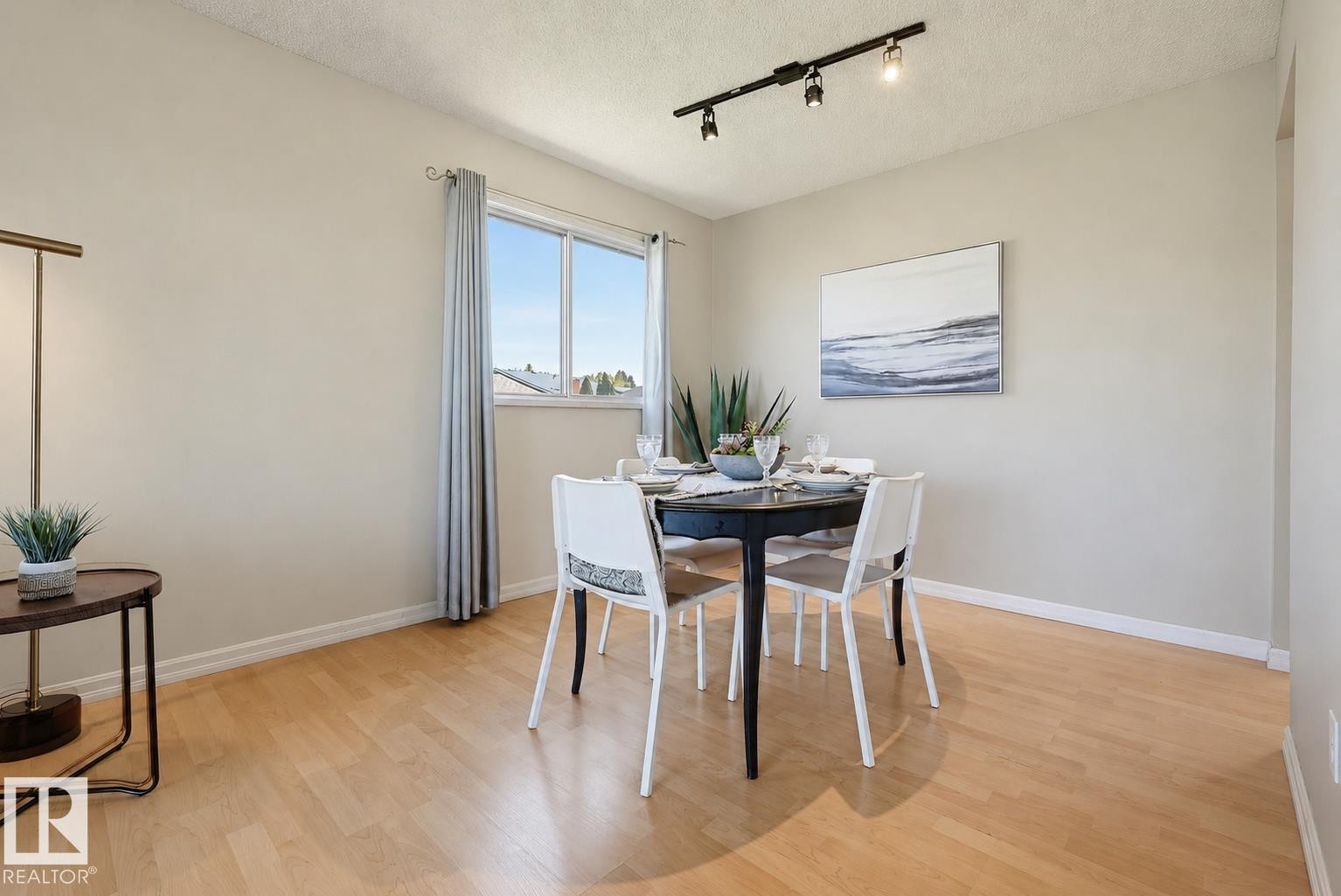 Light wood-finish flooring, track lighting, and a bright window with drapes - 6768 39 Avenue Nw, Edmonton, AB - Indoor Photo Showing Dining Room