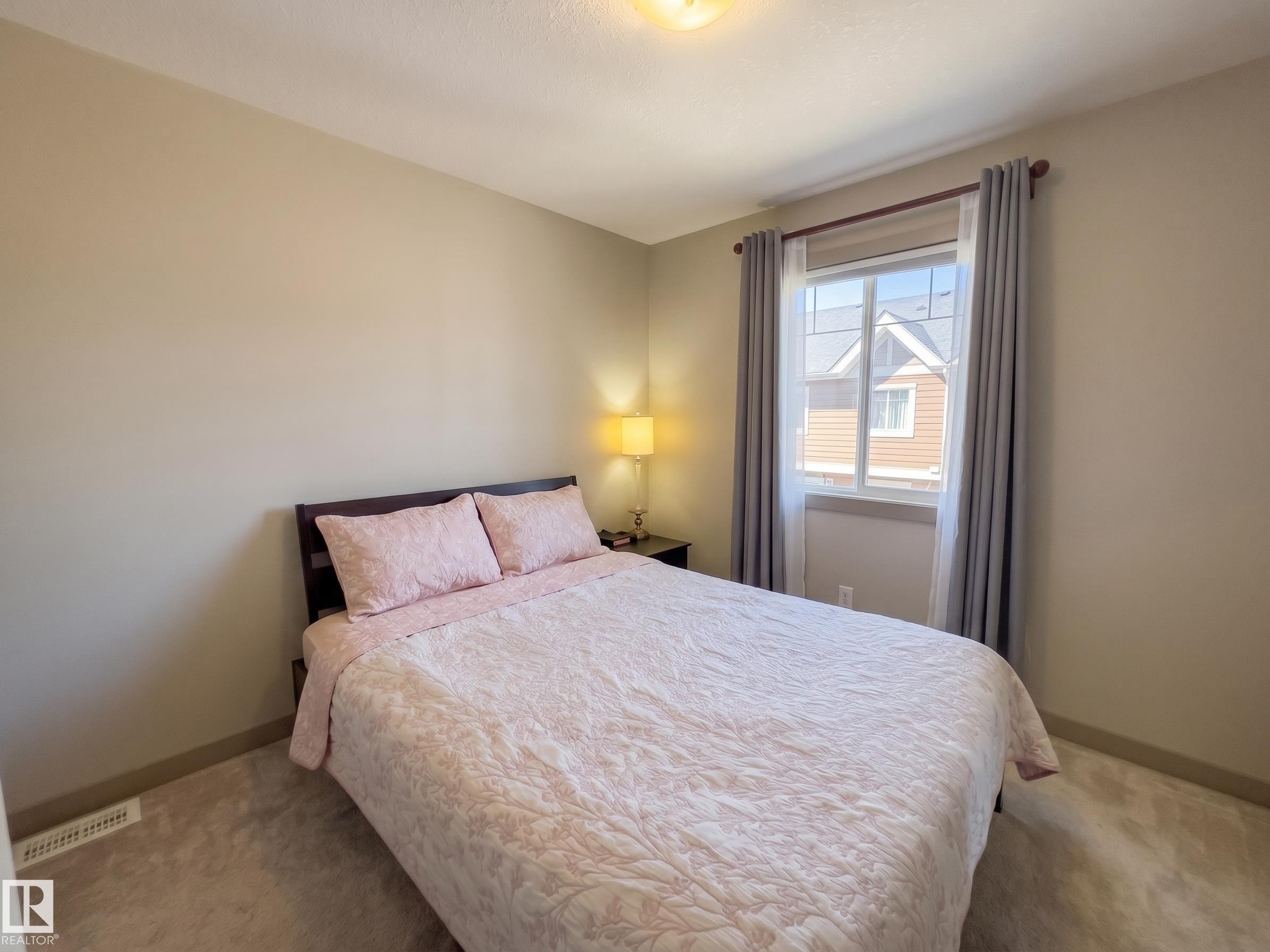 Warm neutral wall tones and a window with a wood-finish curtain rod - #29 1150 Windermere Wy Sw, Edmonton, AB