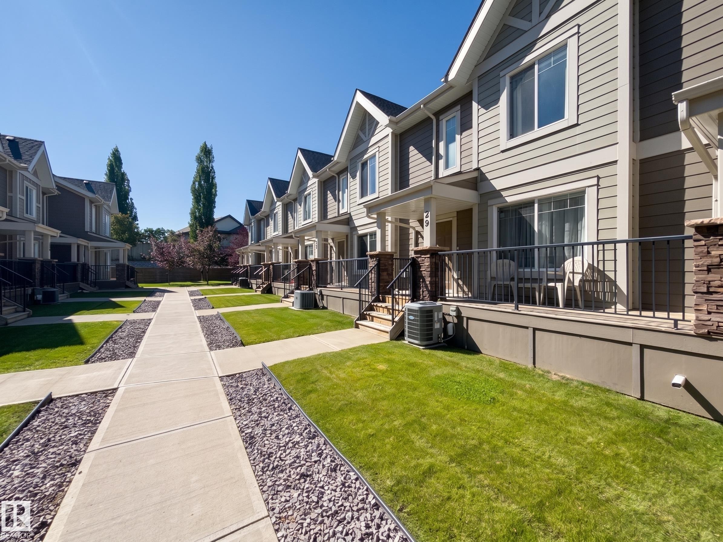 Exterior featuring horizontal siding with stone veneer accents - #29 1150 Windermere Wy Sw, Edmonton, AB