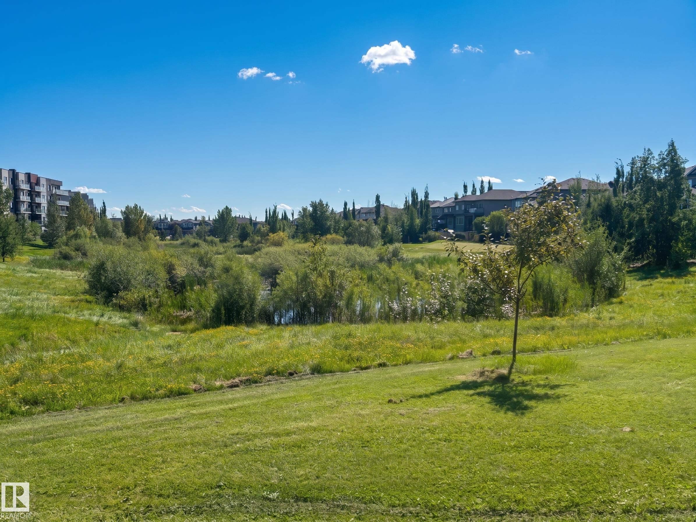 Expansive green space featuring a natural pond and abundant mature trees - #29 1150 Windermere Wy Sw, Edmonton, AB