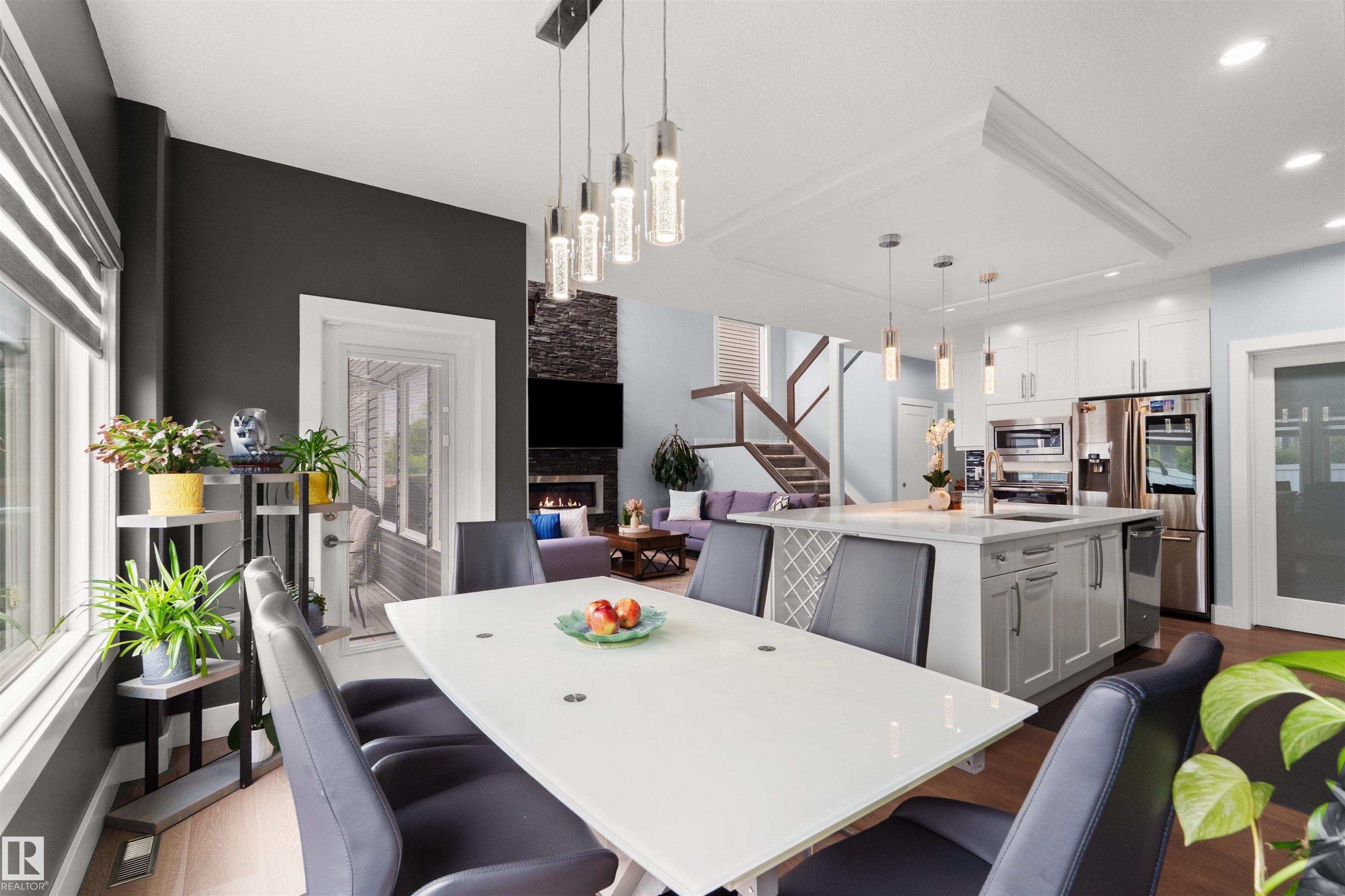 Open-concept living area with a contemporary kitchen island, stainless steel appliances, and a stone-clad fireplace - 16327 17 Avenue Sw, Edmonton, AB - Indoor Photo Showing Dining Room