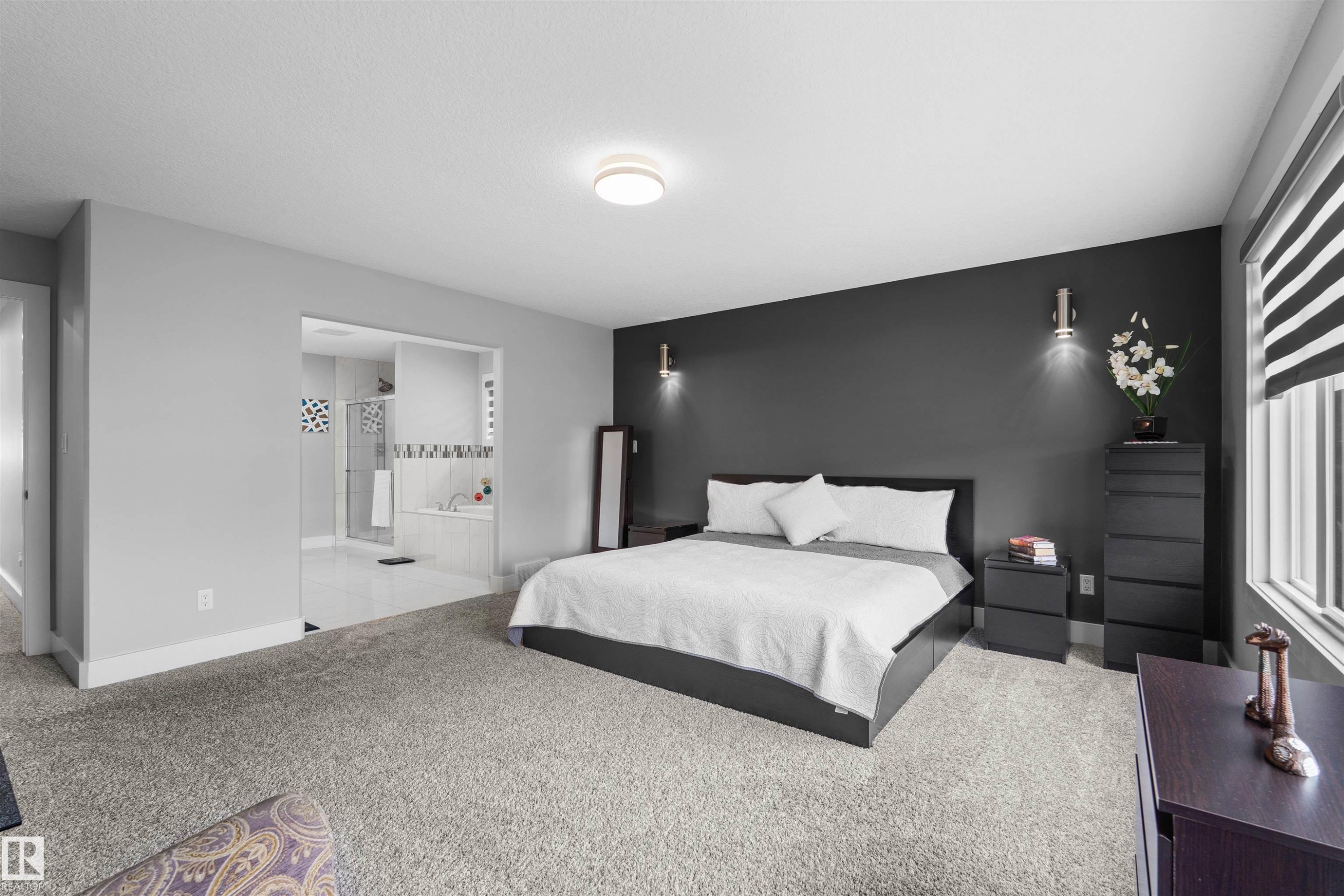 Spacious room with plush carpet flooring, a dark accent wall, and a large window with privacy blinds - 16327 17 Avenue Sw, Edmonton, AB - Indoor Photo Showing Bedroom