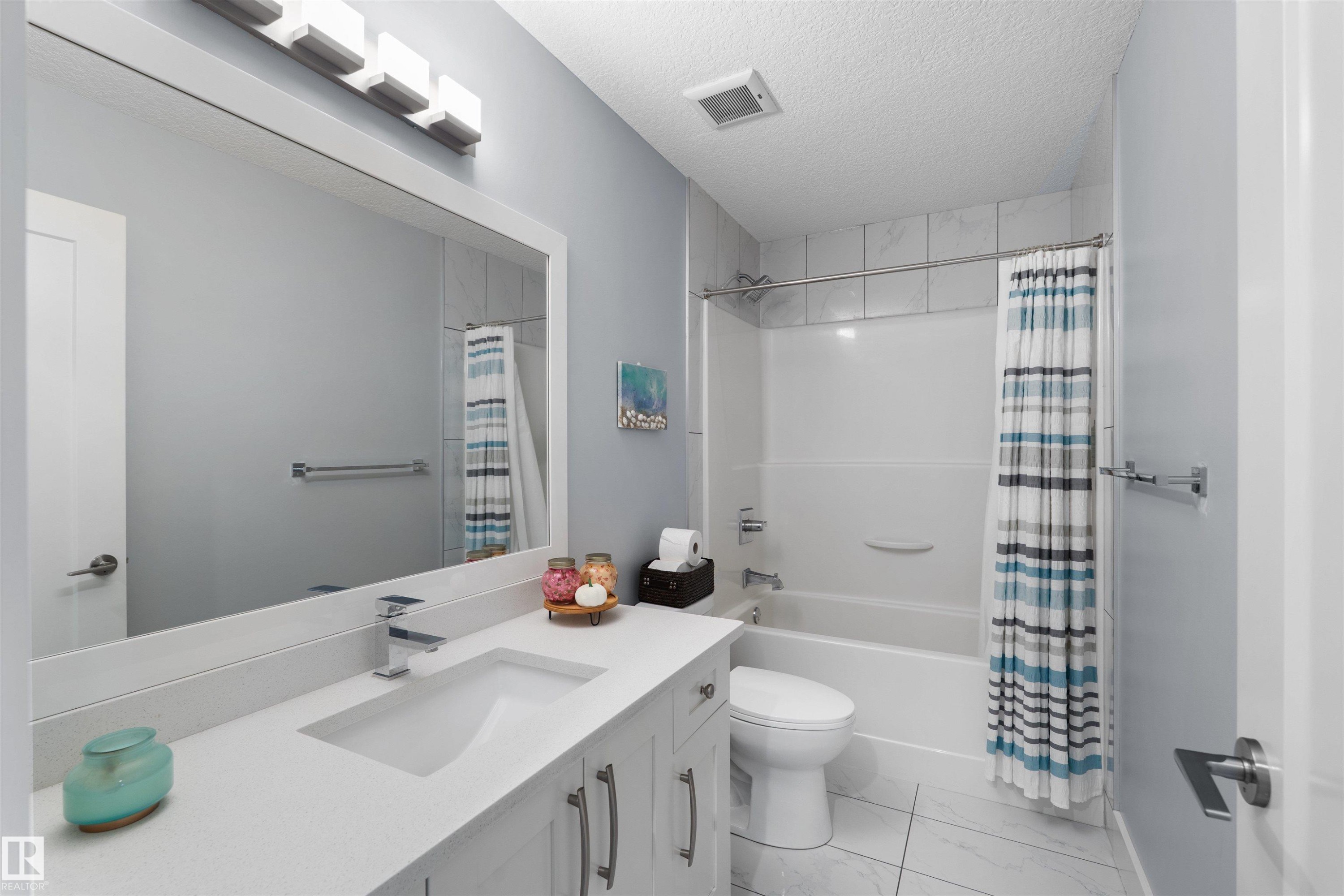 White vanity with an integrated sink, polished chrome faucet, and under-cabinet storage - 16327 17 Avenue Sw, Edmonton, AB - Indoor Photo Showing Bathroom