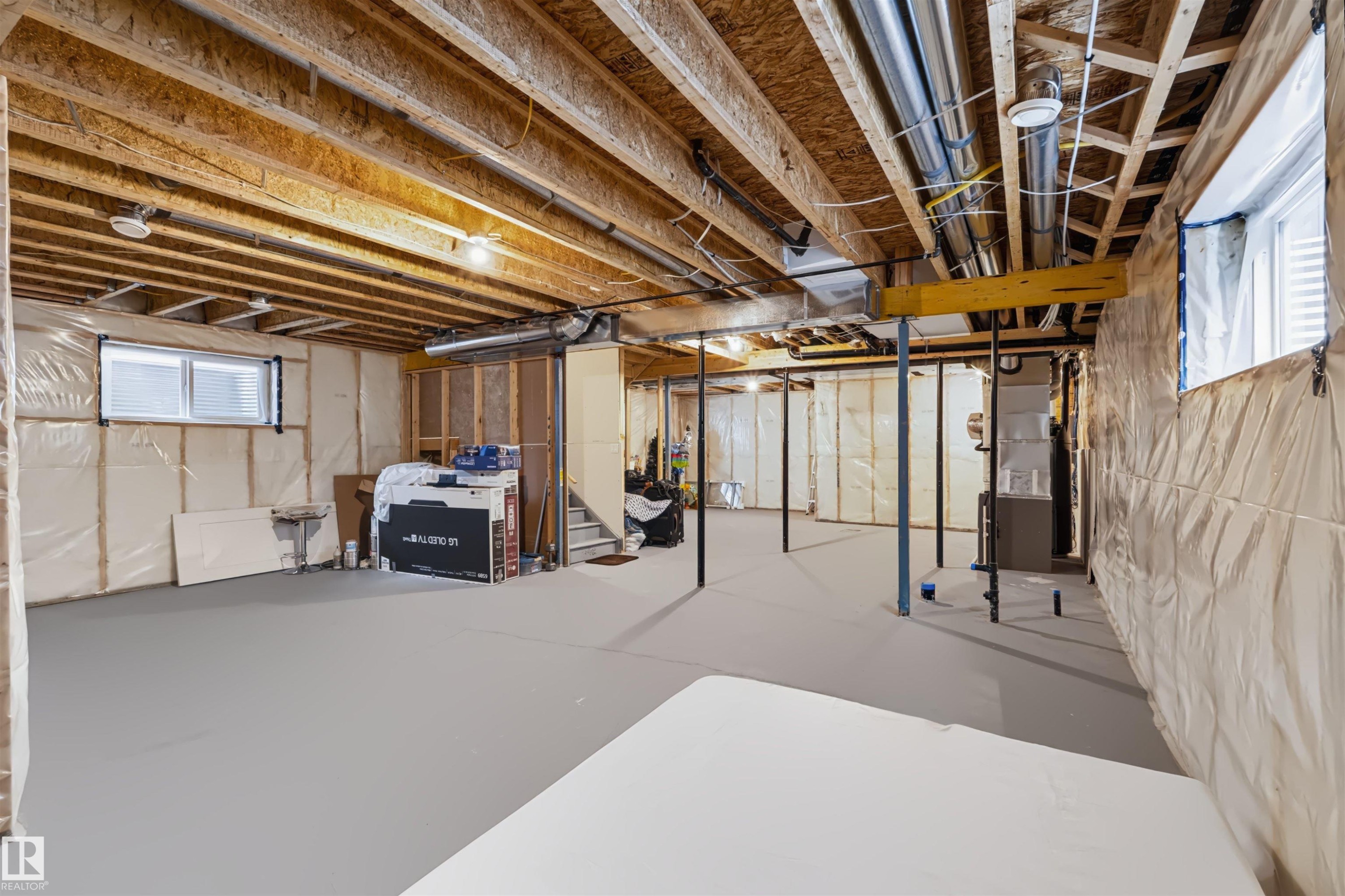 Unfinished lower level featuring exposed wood joists, structural support beams, concrete flooring, and multiple windows - 16327 17 Avenue Sw, Edmonton, AB - Indoor Photo Showing Basement