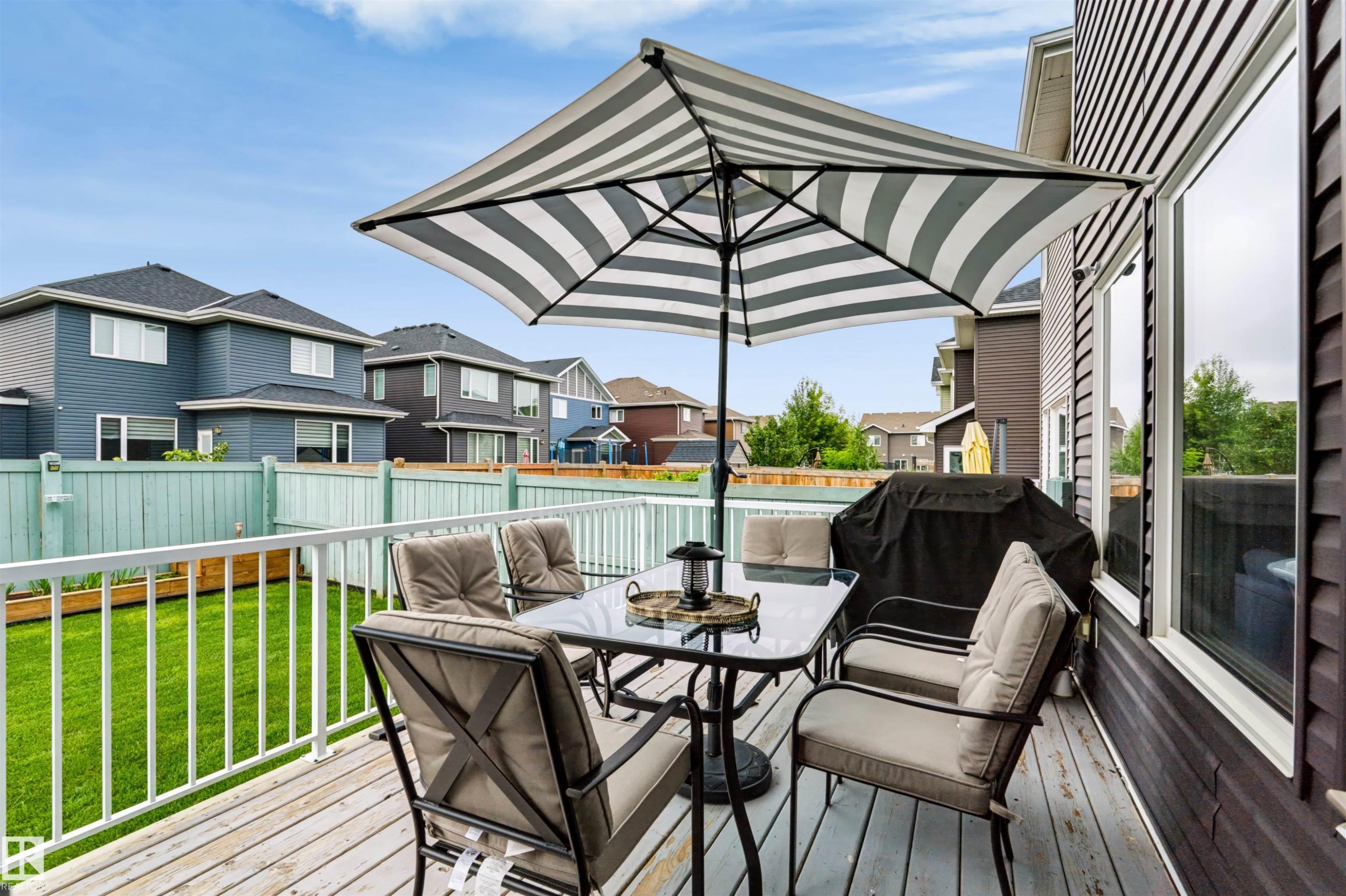 Raised wood-finish deck with white railings and an expansive green space - 16327 17 Avenue Sw, Edmonton, AB - Outdoor With Deck Patio Veranda With Exterior