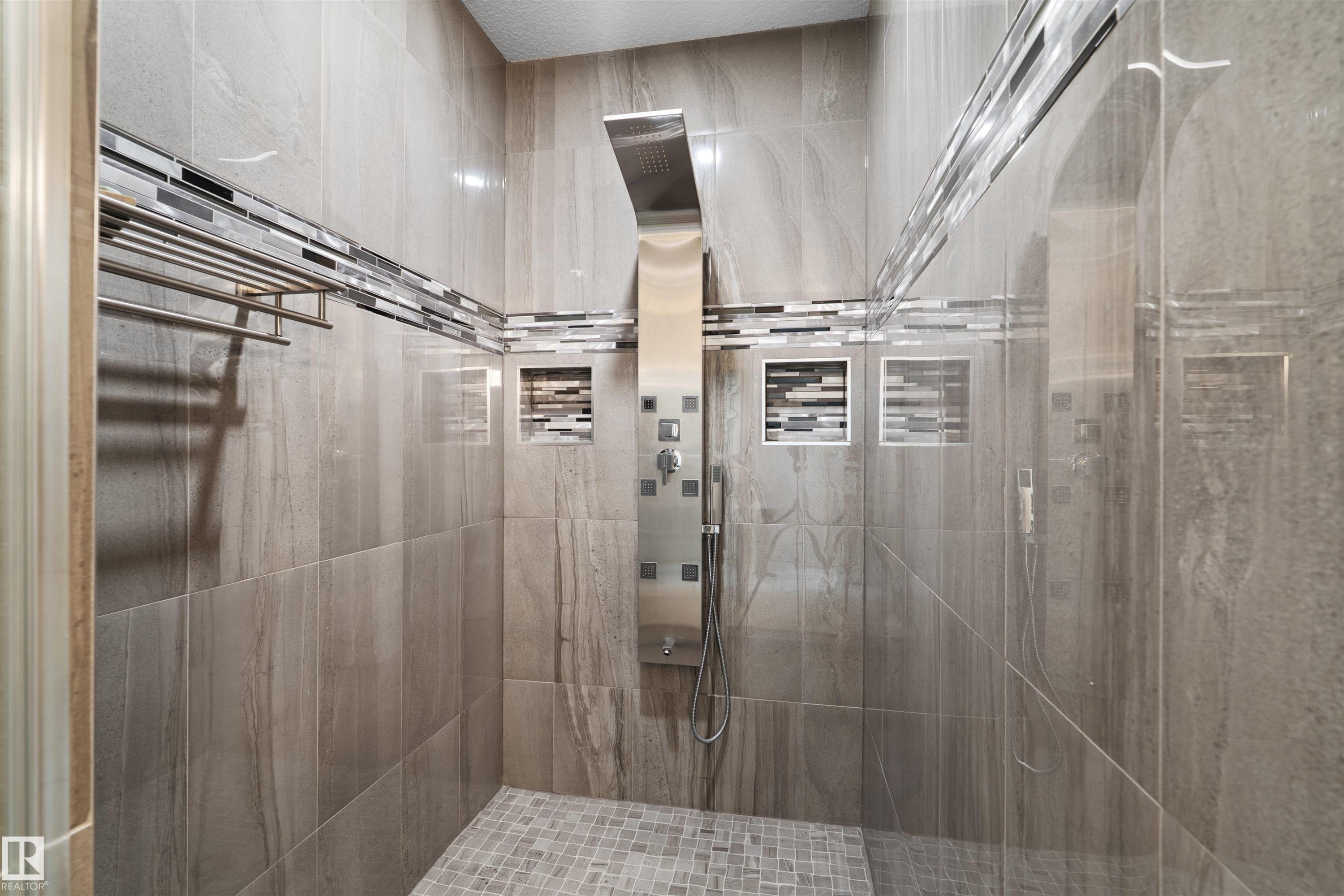 Tiled shower enclosure featuring a multi-function shower panel, recessed niches with mosaic tile accents, and a mosaic tiled shower floor - 16327 17 Avenue Sw, Edmonton, AB - Indoor Photo Showing Bathroom