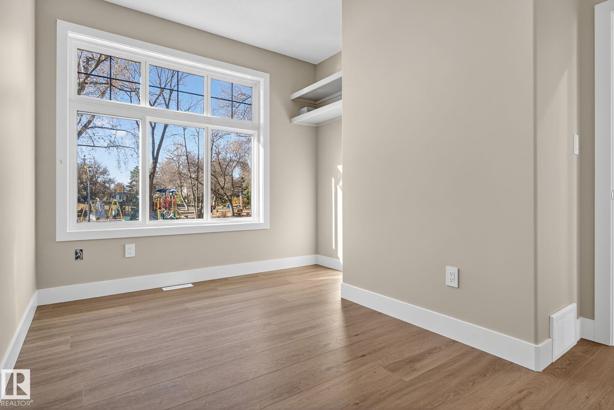 Large multi-pane window, wood-finish flooring, built-in shelving, neutral wall color, white trim - 9736 73 Avenue Nw, Edmonton, AB