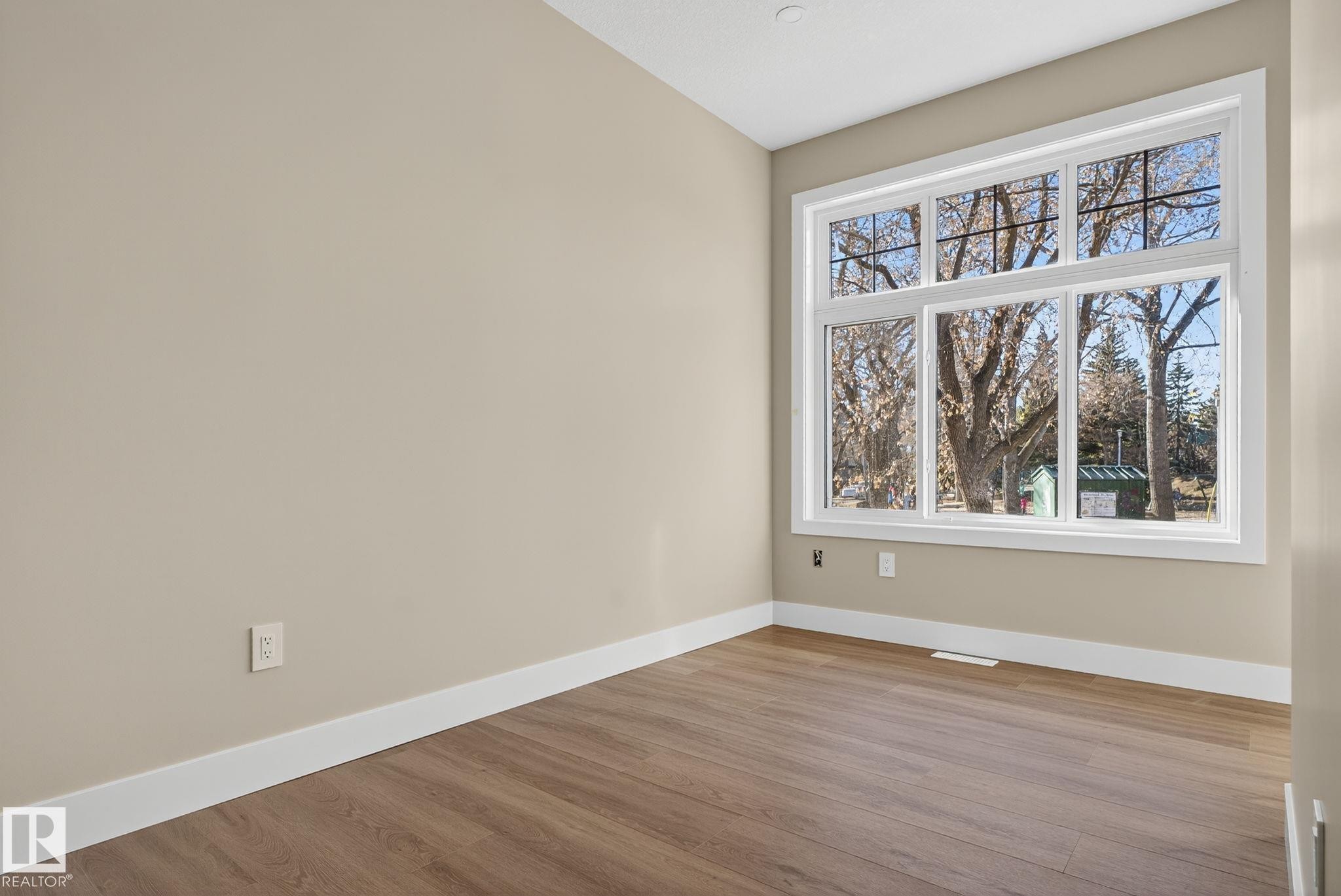 Expansive window offering abundant natural light, wood-finish flooring, recessed ceiling lighting, and neutral wall tones - 9736 73 Avenue Nw, Edmonton, AB