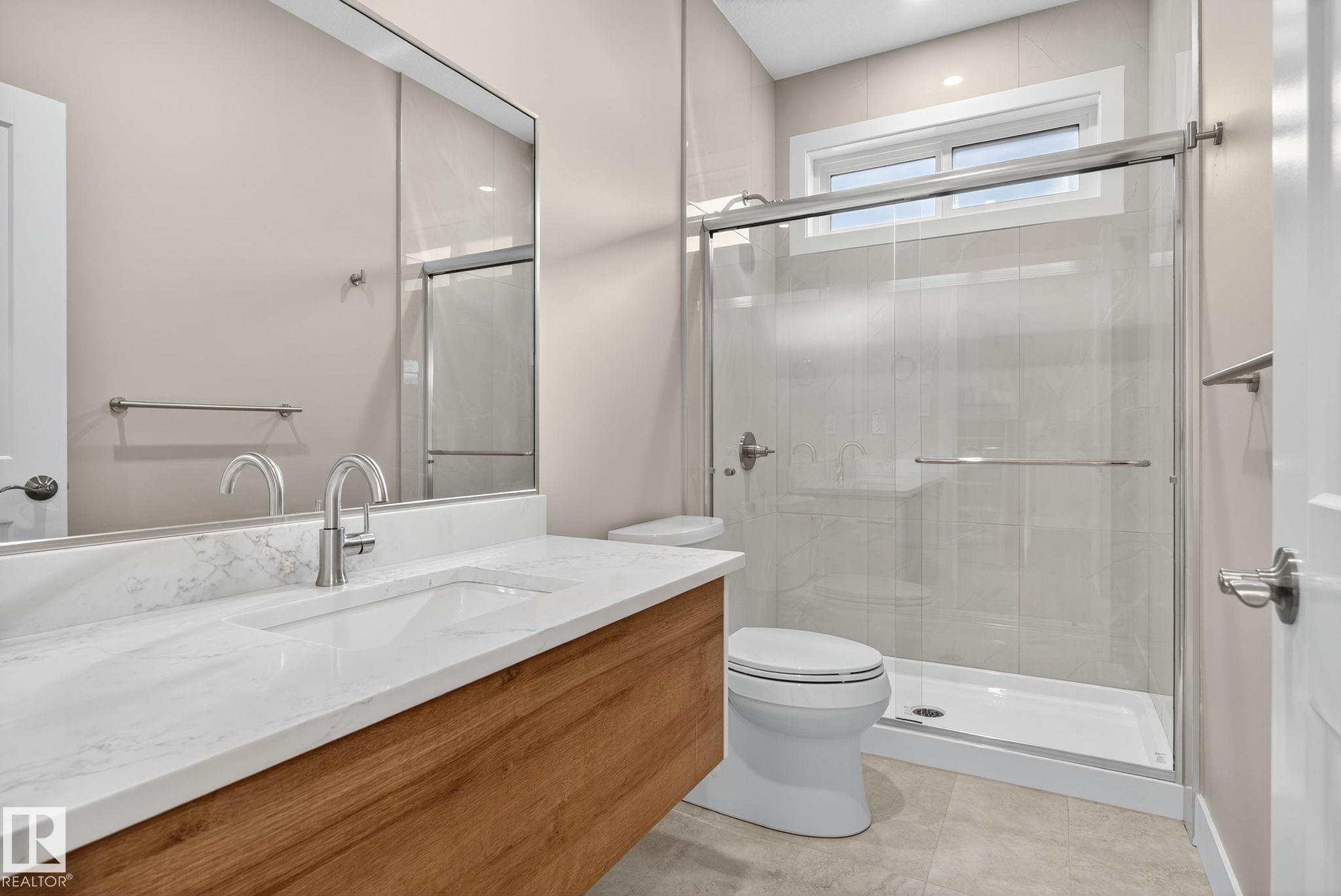 Wood-finish vanity with an integrated rectangular sink and stone-finish countertop - 9736 73 Avenue Nw, Edmonton, AB