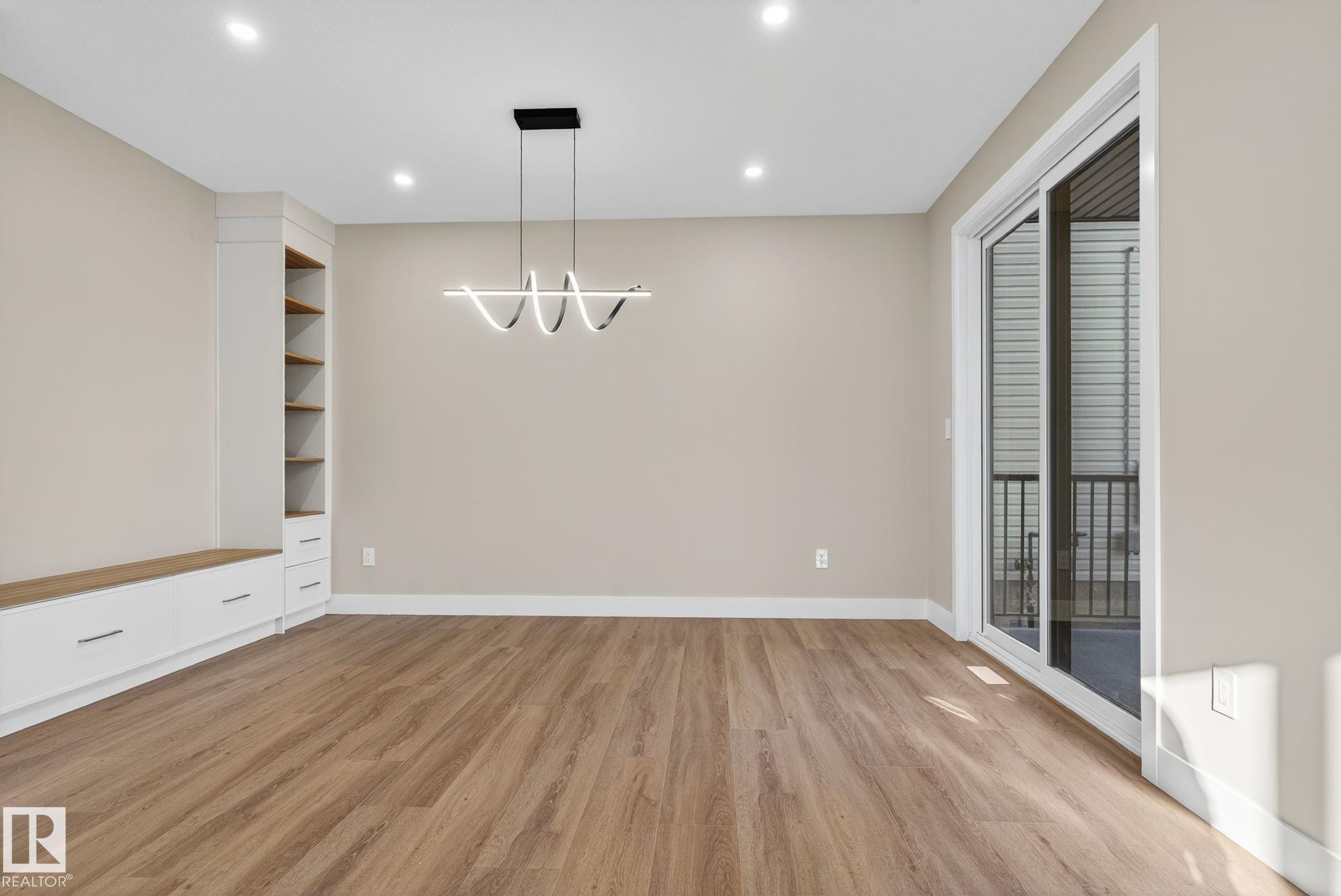 Built-in cabinetry with wood-finish shelving, contemporary pendant lighting, recessed ceiling lights, wood-finish flooring, and sliding glass doors - 9736 73 Avenue Nw, Edmonton, AB