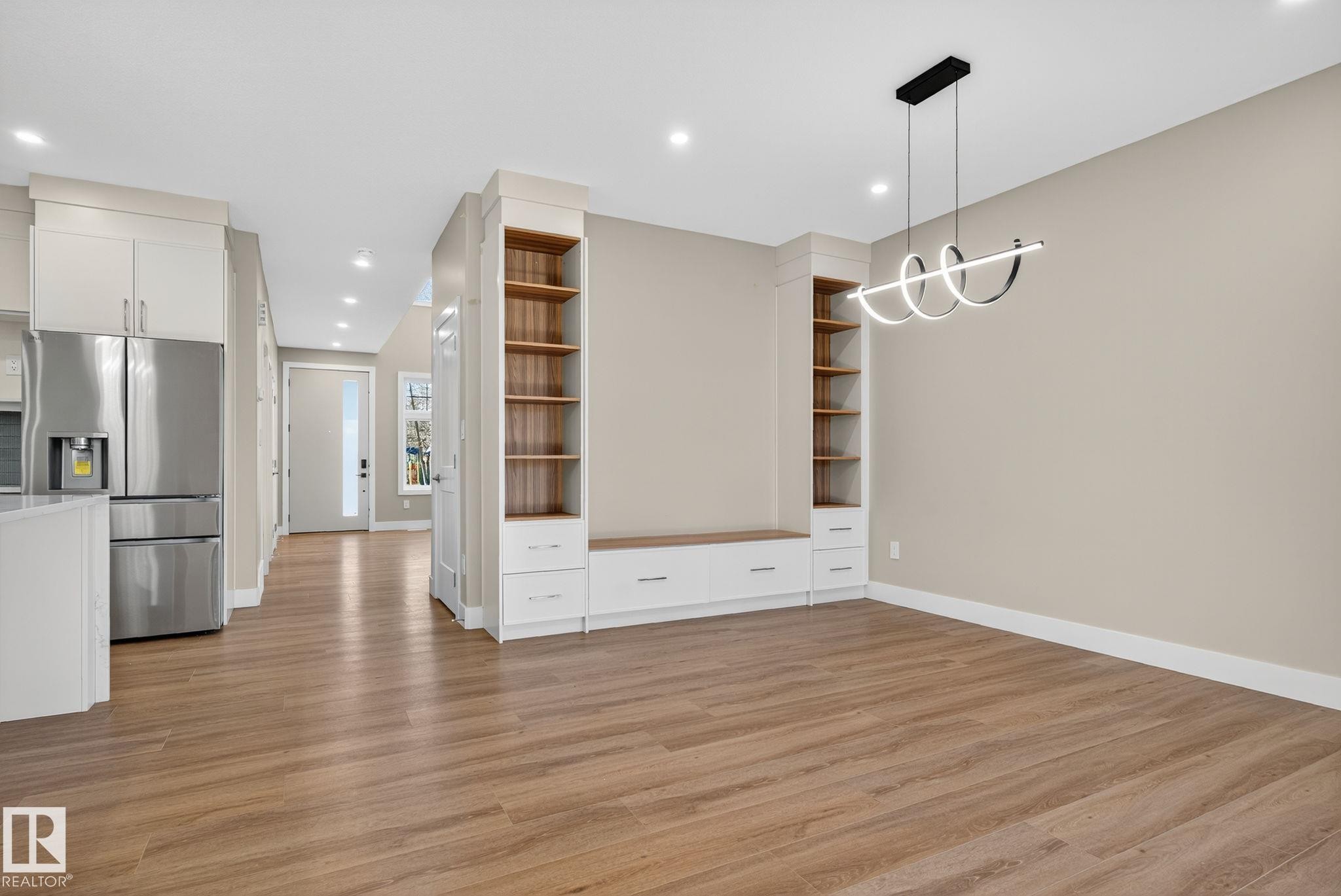 Open-concept living area with wood-finish flooring, recessed lighting, and a contemporary chandelier - 9736 73 Avenue Nw, Edmonton, AB