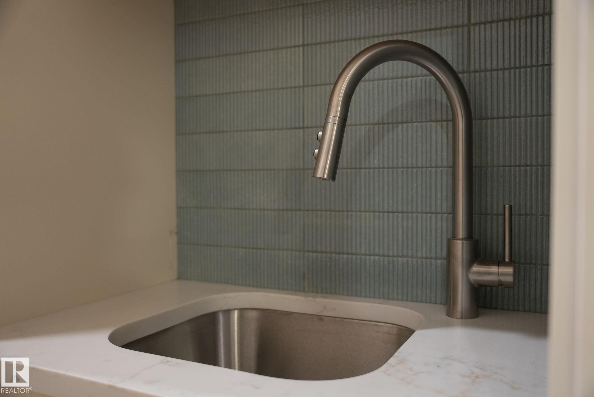 Stainless steel sink with a high-arc faucet, set within a white countertop - 9736 73 Avenue Nw, Edmonton, AB