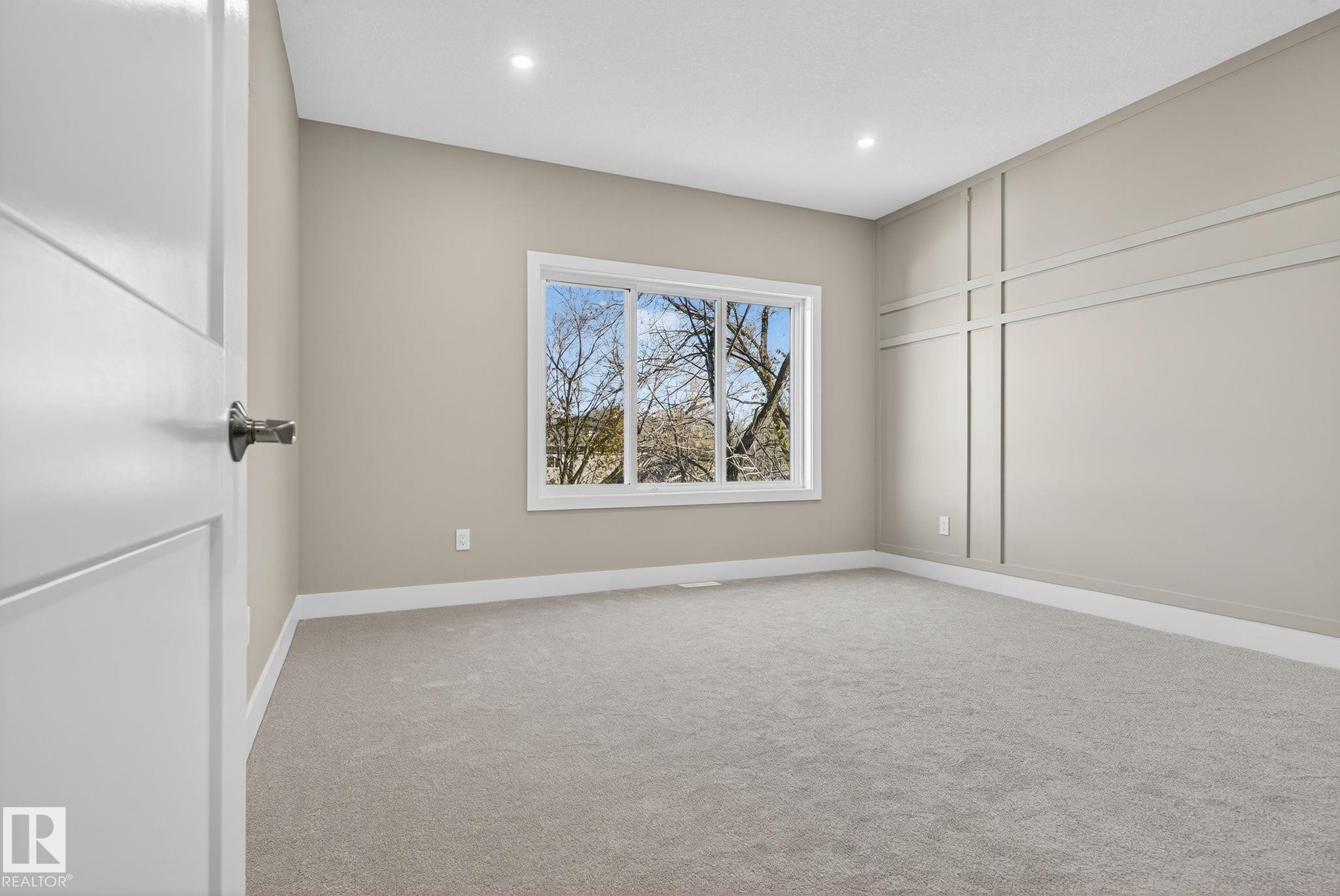 Neutral wall paint, recessed lighting, white trim, sliding window, and accent wall paneling - 9736 73 Avenue Nw, Edmonton, AB
