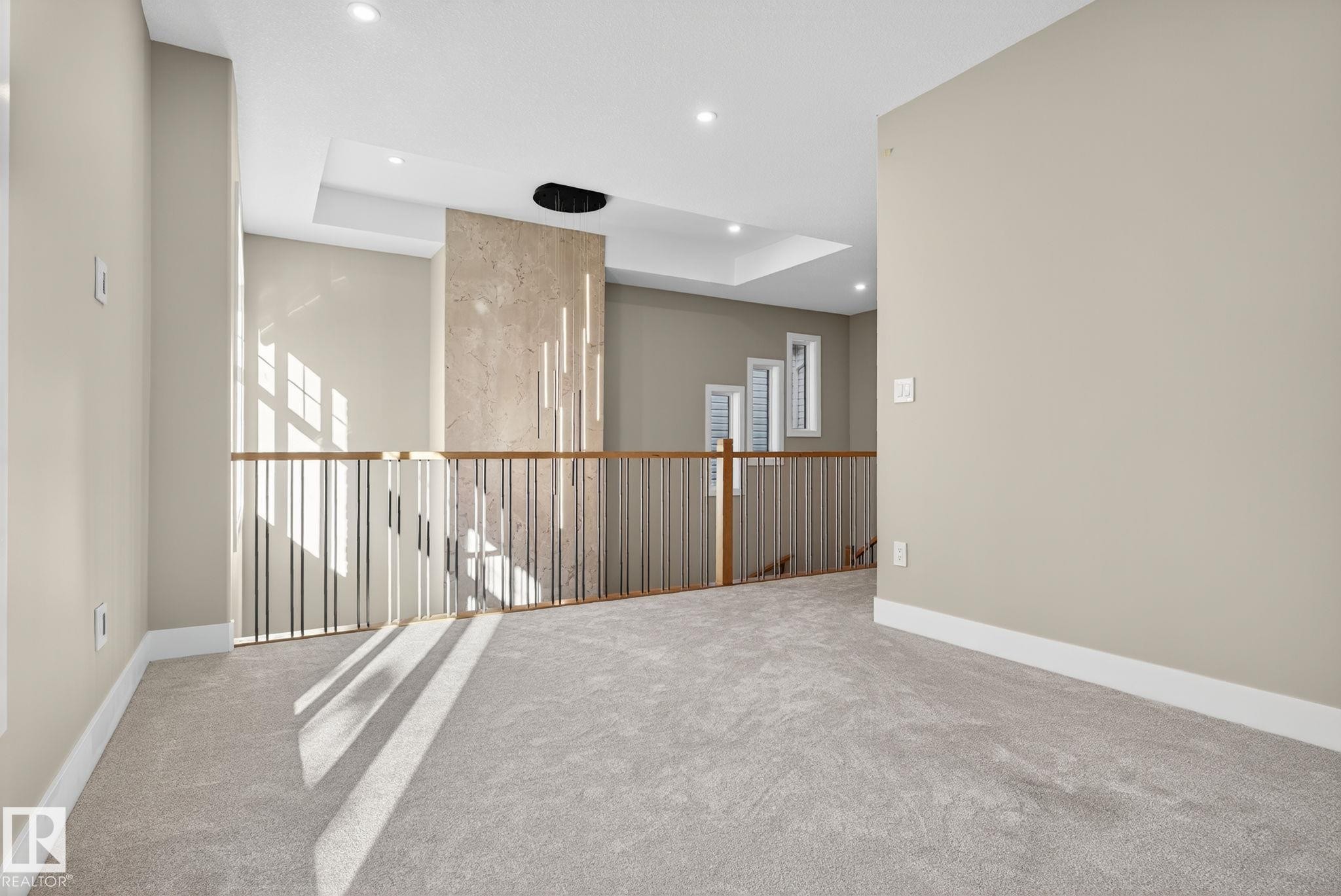 Carpeted loft area featuring a tray ceiling, recessed lighting, and a modern metal and wood railing - 9736 73 Avenue Nw, Edmonton, AB