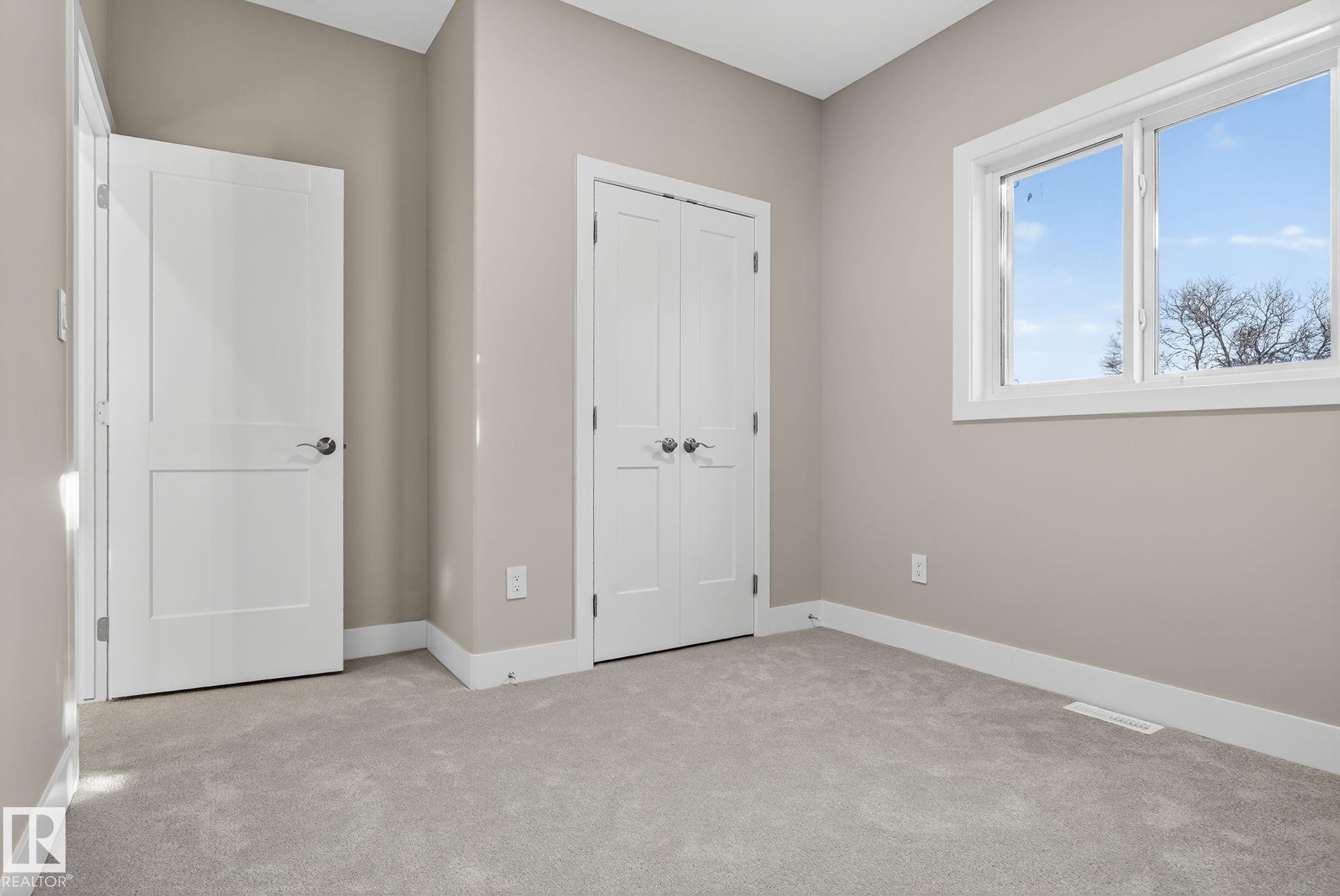 Neutral wall tones, light gray carpeting, crisp white trim, and a window with a multi-pane design - 9736 73 Avenue Nw, Edmonton, AB