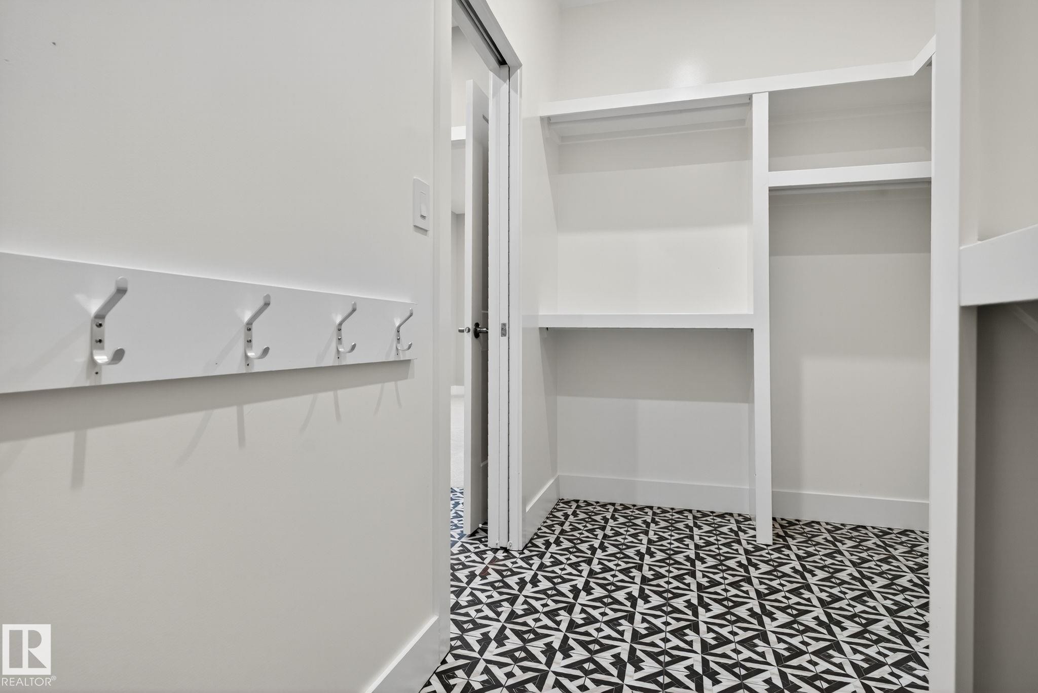 Built-in coat rack with five hooks, custom shelving, multiple hanging rods, and patterned floor tiling - 9736 73 Avenue Nw, Edmonton, AB
