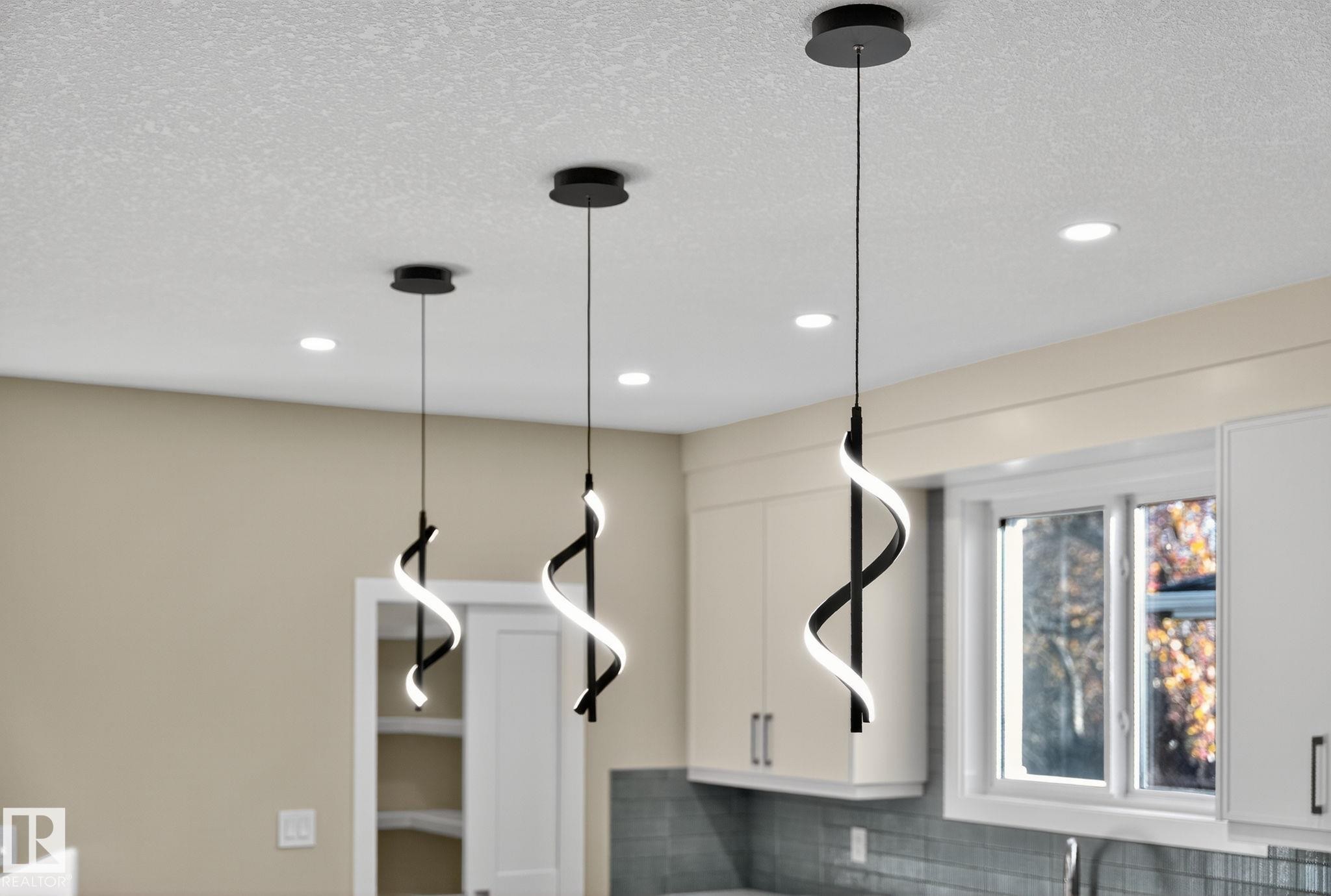 Recessed ceiling lights, white shaker-style cabinetry, a white window frame, and a subway tile backsplash - 9736 73 Avenue Nw, Edmonton, AB