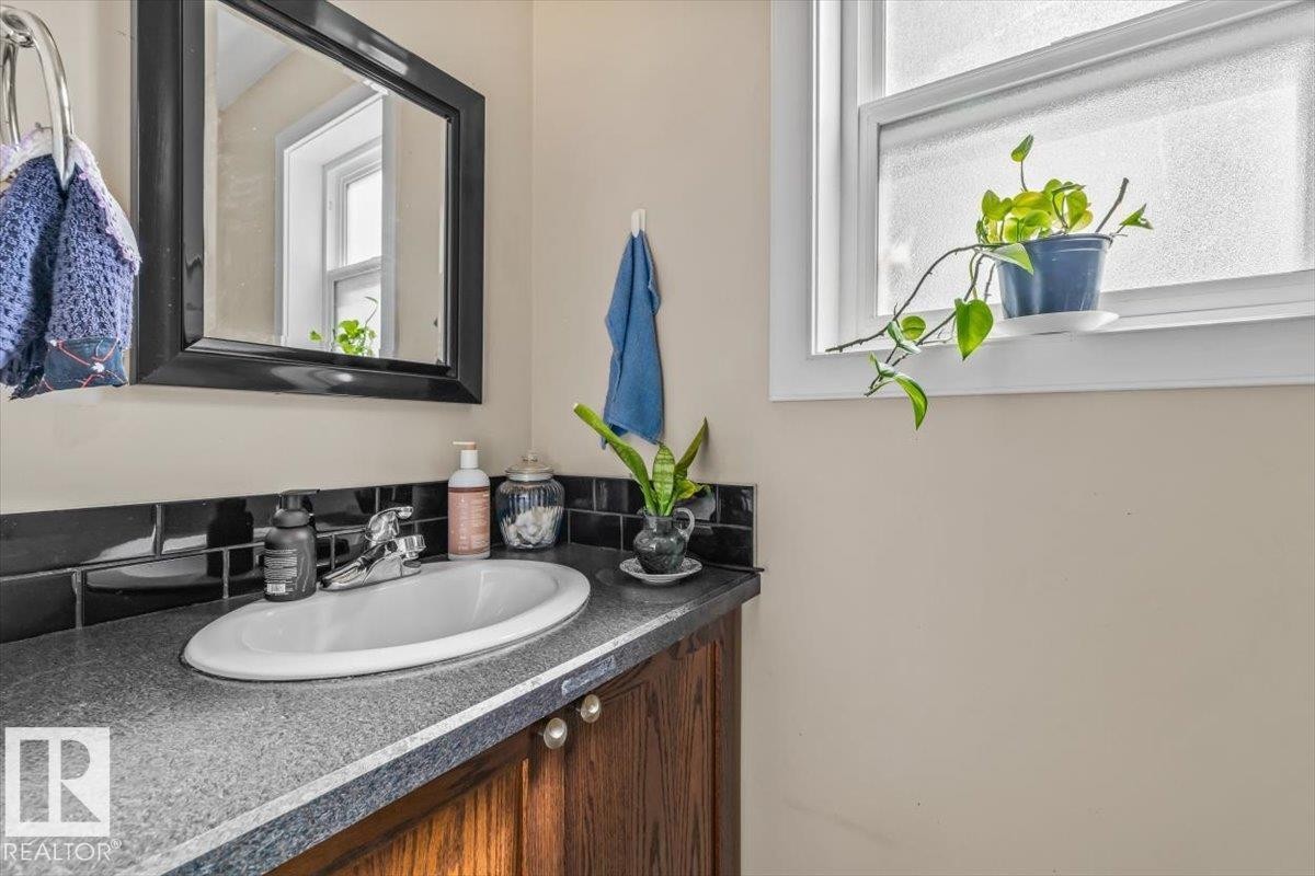 Wood-finish vanity with a surface-mounted sink, chrome faucet, and dark countertop - 11436 88 Street Nw, Edmonton, AB - Indoor Photo Showing Bathroom