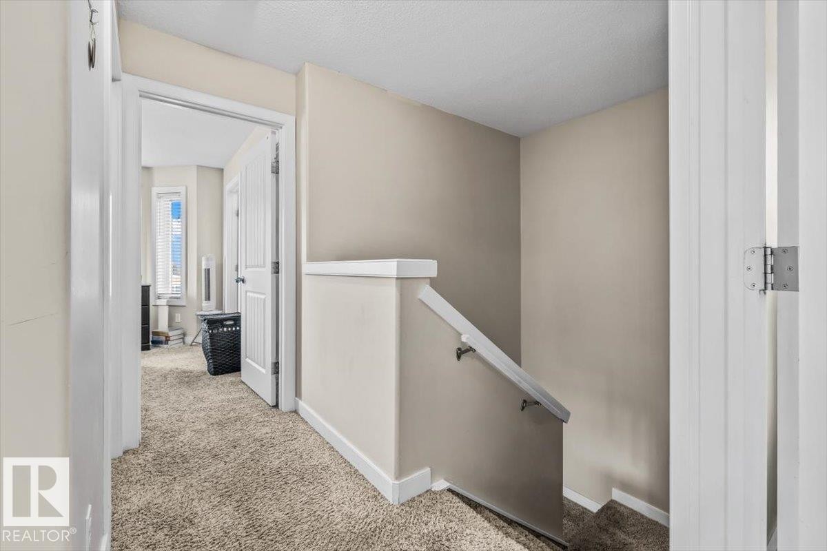 Carpeted hallway with painted walls and a staircase featuring a white handrail - 11436 88 Street Nw, Edmonton, AB - Indoor Photo Showing Other Room