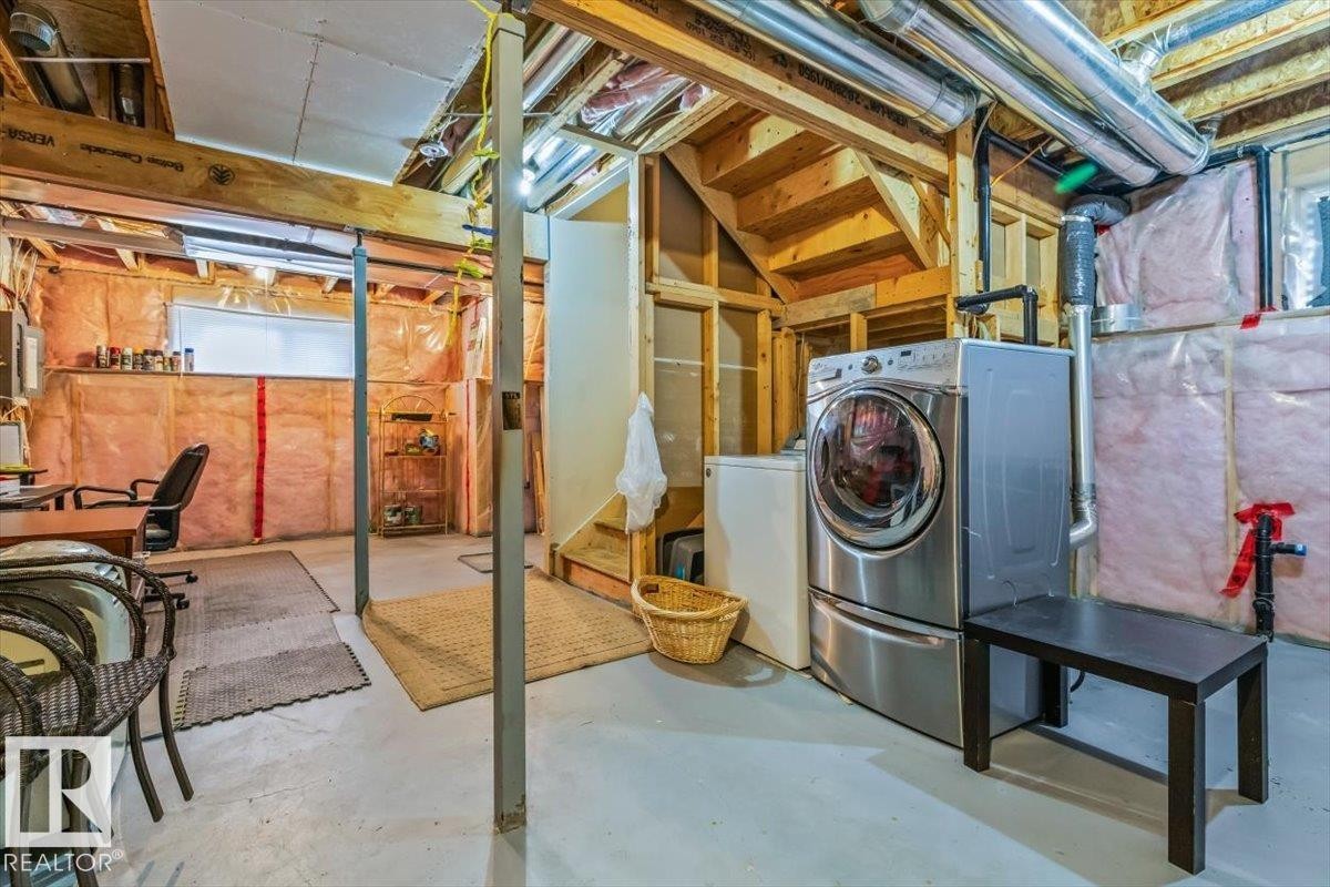 Unfinished basement with exposed wood framing, concrete flooring, and an installed laundry area - 11436 88 Street Nw, Edmonton, AB - Indoor Photo Showing Laundry Room