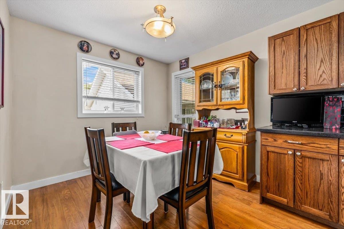 Wood-finish flooring, warm neutral wall tones, and a single window with blinds - 11436 88 Street Nw, Edmonton, AB - Indoor Photo Showing Dining Room
