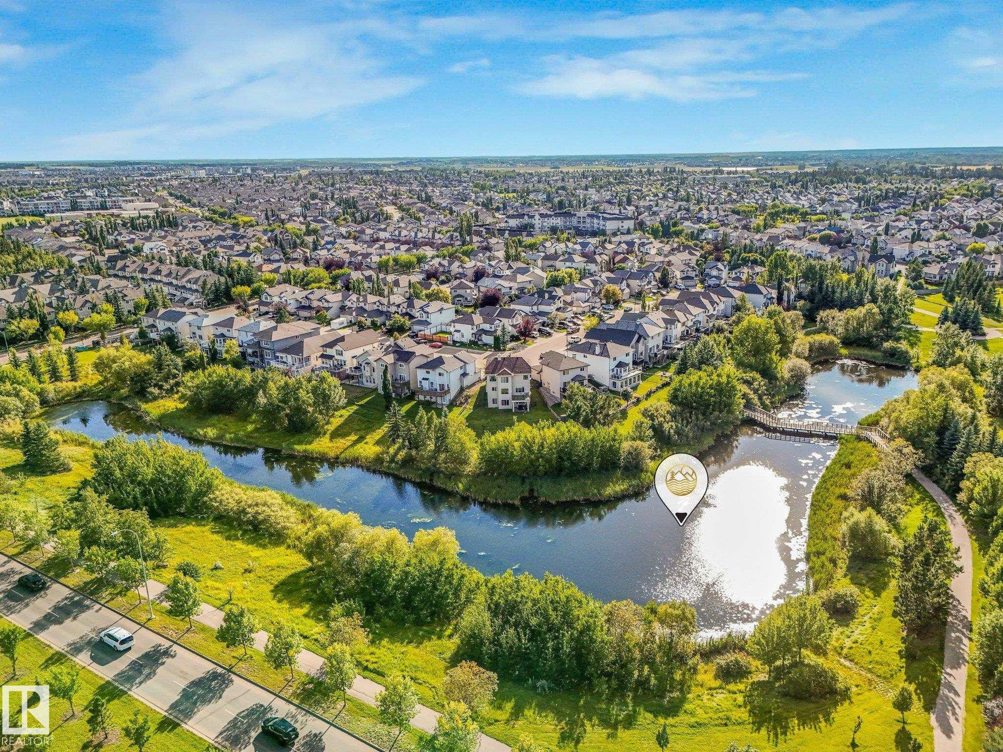 Residential neighborhood with a prominent water feature, surrounded by mature trees and paved walking paths - 1142 Barnes Way Sw, Edmonton, AB - Outdoor With View
