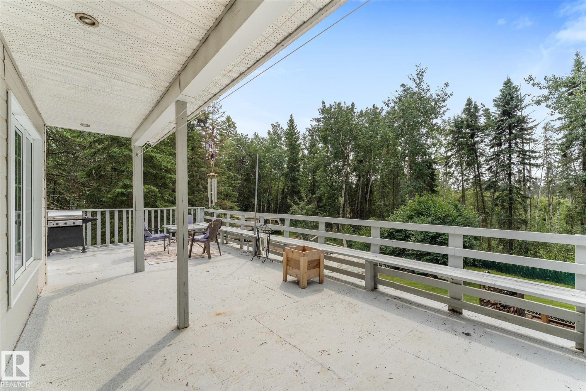 Expansive outdoor deck with a solid railing, offering a private setting surrounded by mature trees - 2, 59031 Range Rd 232, Rural Thorhild County, AB - Outdoor With Deck Patio Veranda