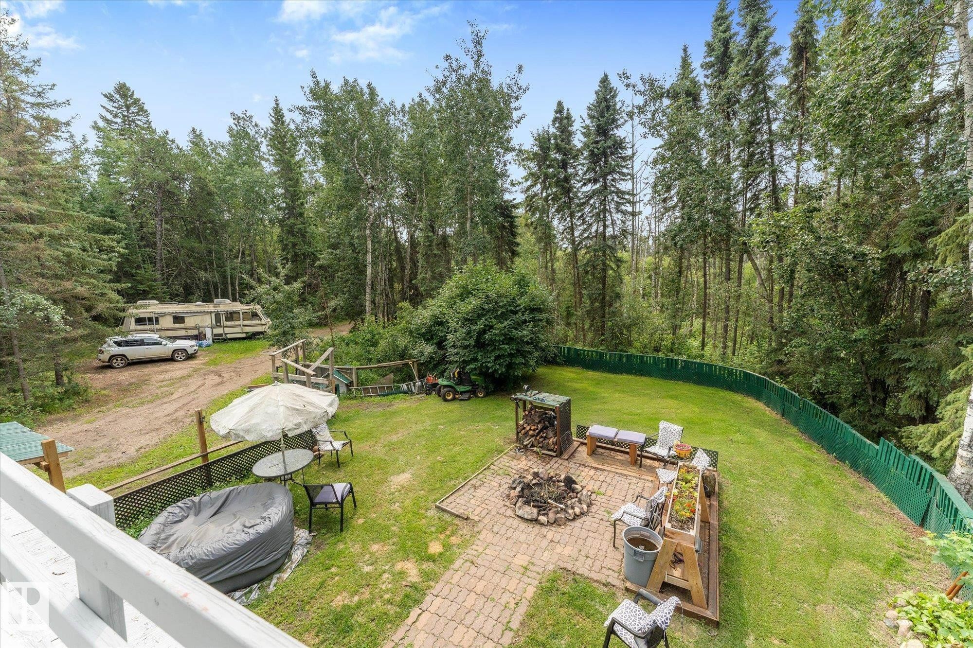 Expansive backyard featuring a lush lawn, mature trees, and a paver patio with a built-in fire pit - 2, 59031 Range Rd 232, Rural Thorhild County, AB - Outdoor