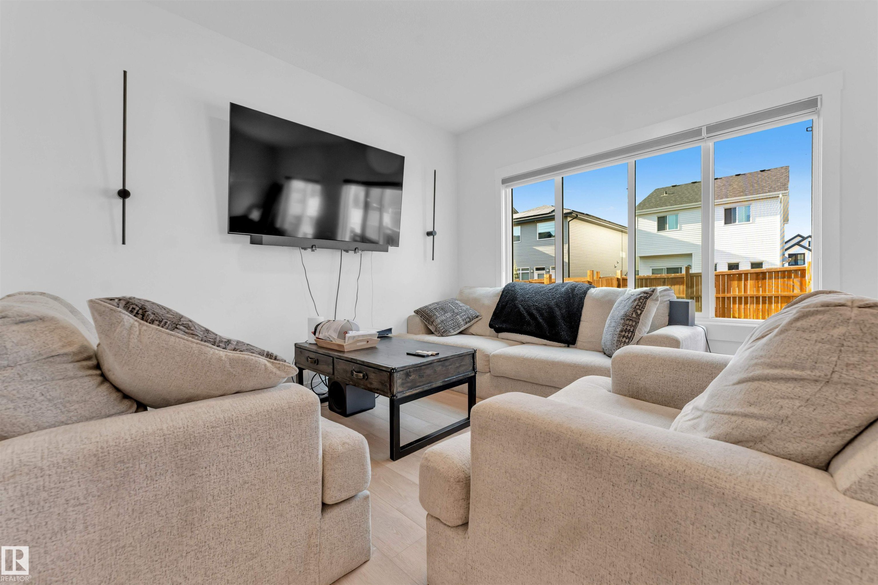 Large windows, hard-surface flooring, bright white walls, and contemporary wall-mounted lighting - 3236 Chernowski Way Sw, Edmonton, AB - Indoor Photo Showing Living Room