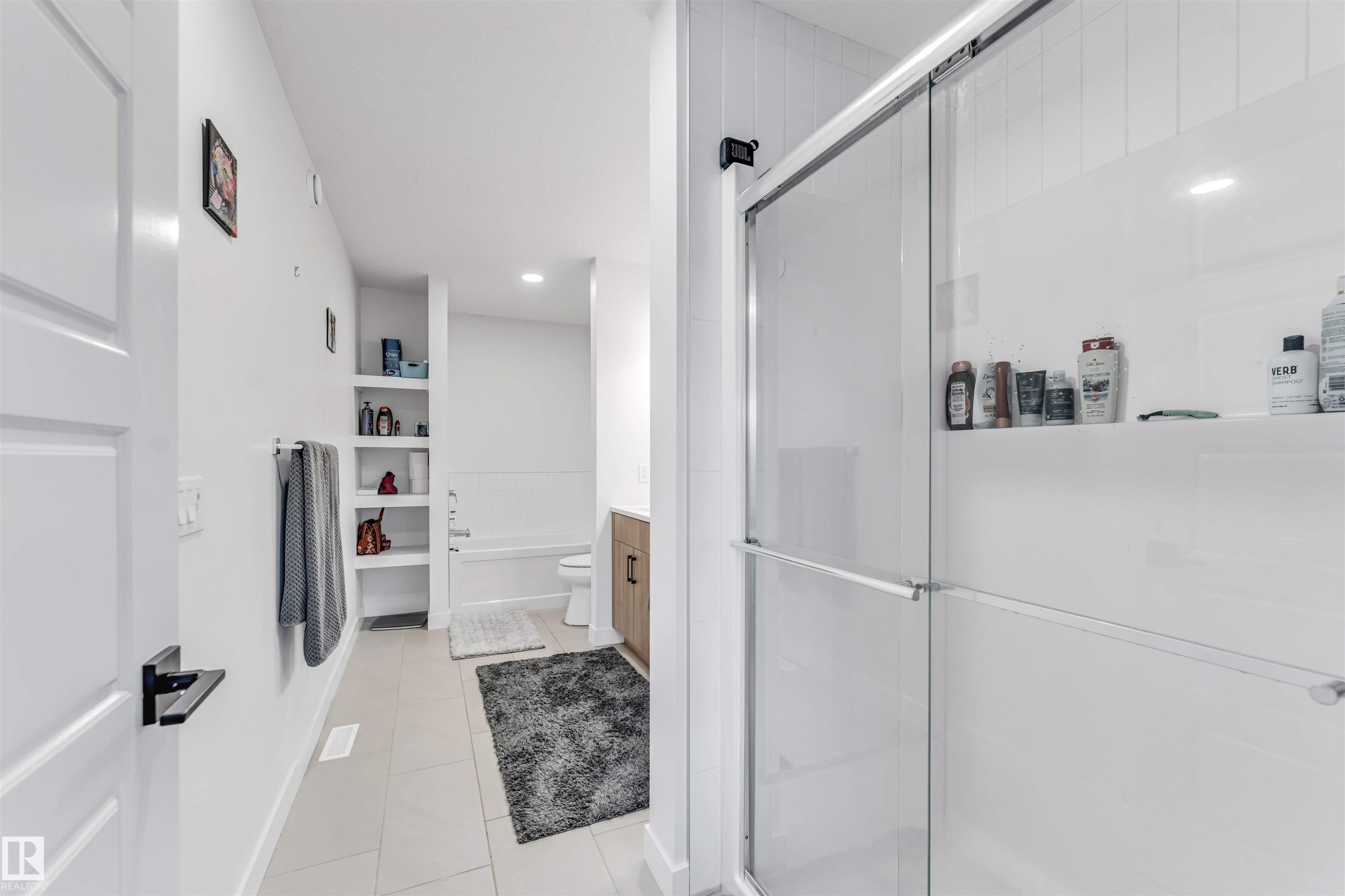 Glass-enclosed shower with white tiled walls, built-in recessed shelving, a separate bathtub, and tile flooring - 3236 Chernowski Way Sw, Edmonton, AB - Indoor Photo Showing Bathroom