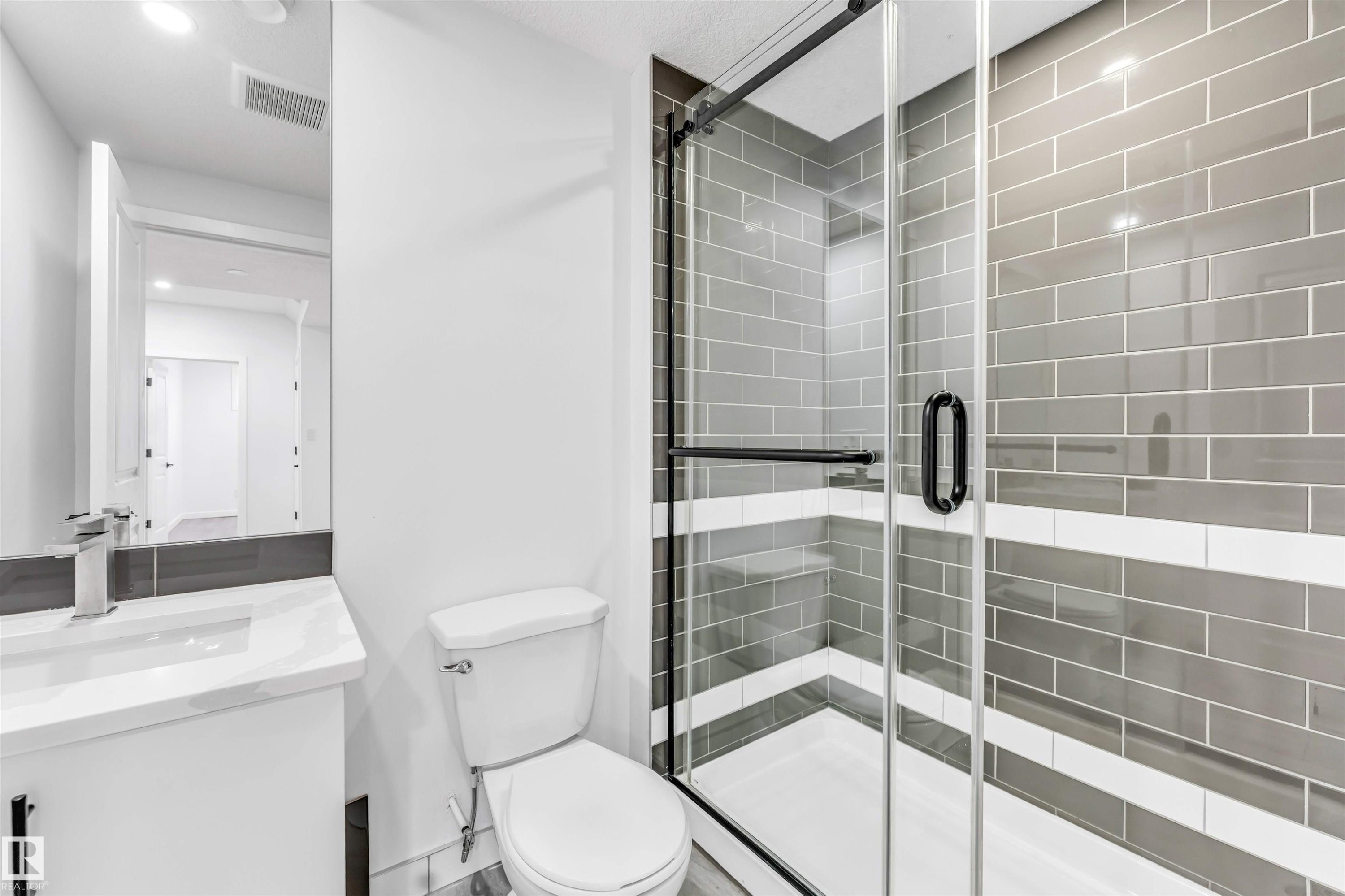Walk-in shower with clear glass enclosure, gray subway tile, and a white accent band - 3236 Chernowski Way Sw, Edmonton, AB - Indoor Photo Showing Bathroom