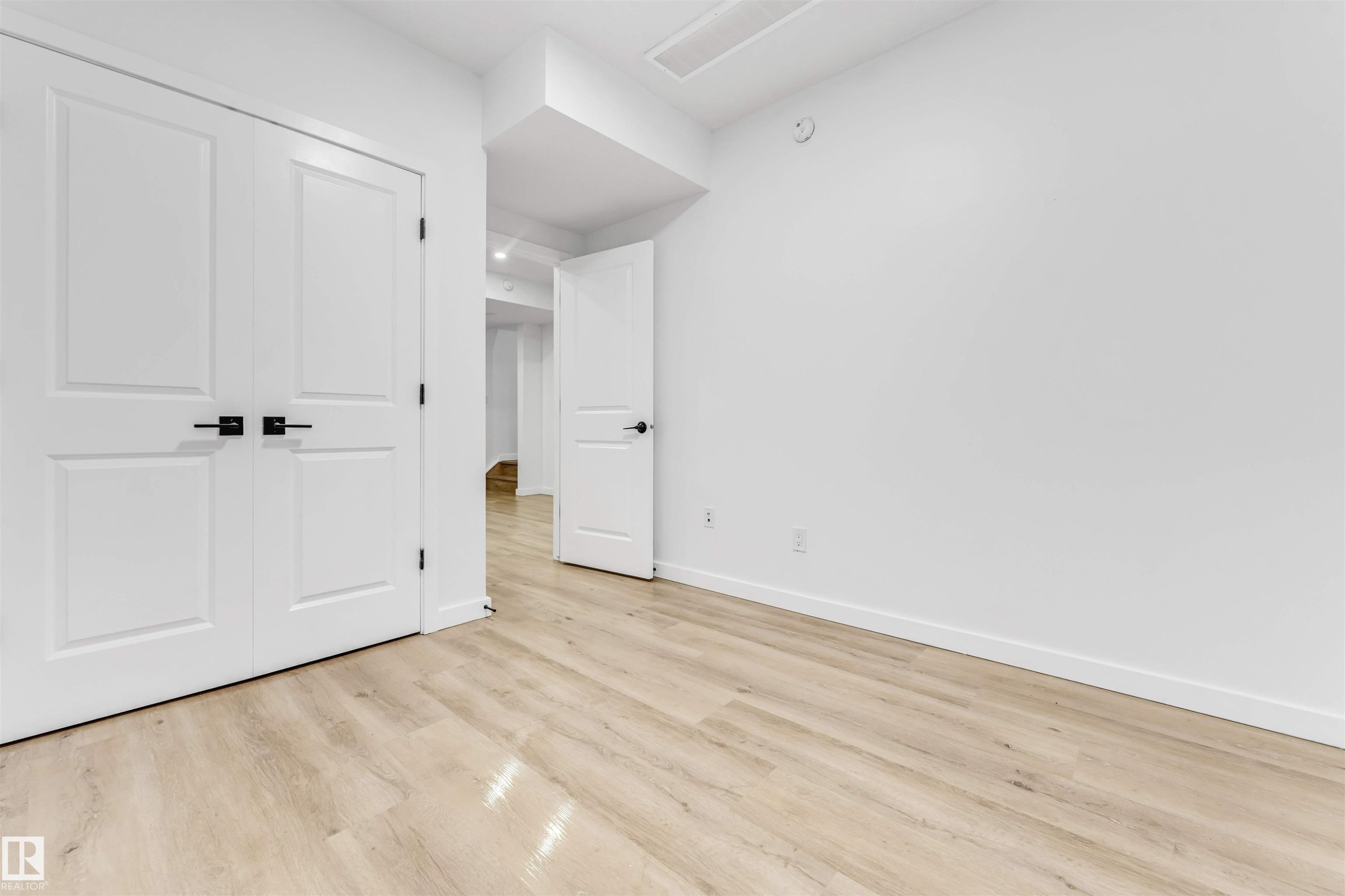 Light wood-finish flooring, white walls, and white trim - 3236 Chernowski Way Sw, Edmonton, AB - Indoor Photo Showing Other Room