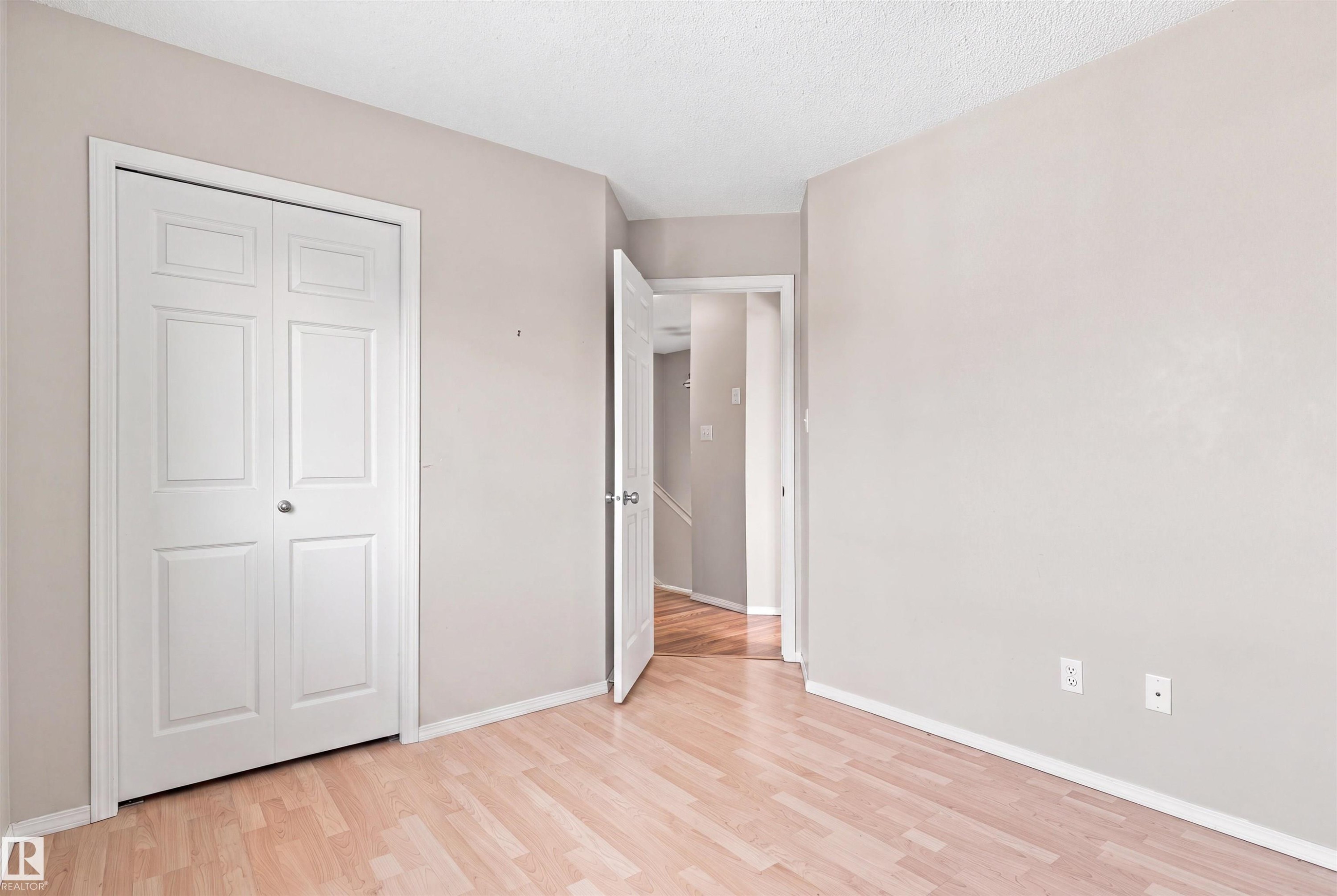 Wood-finish flooring with white trim and a neutral paint palette - 204 84 Street Sw, Edmonton, AB - Indoor Photo Showing Other Room