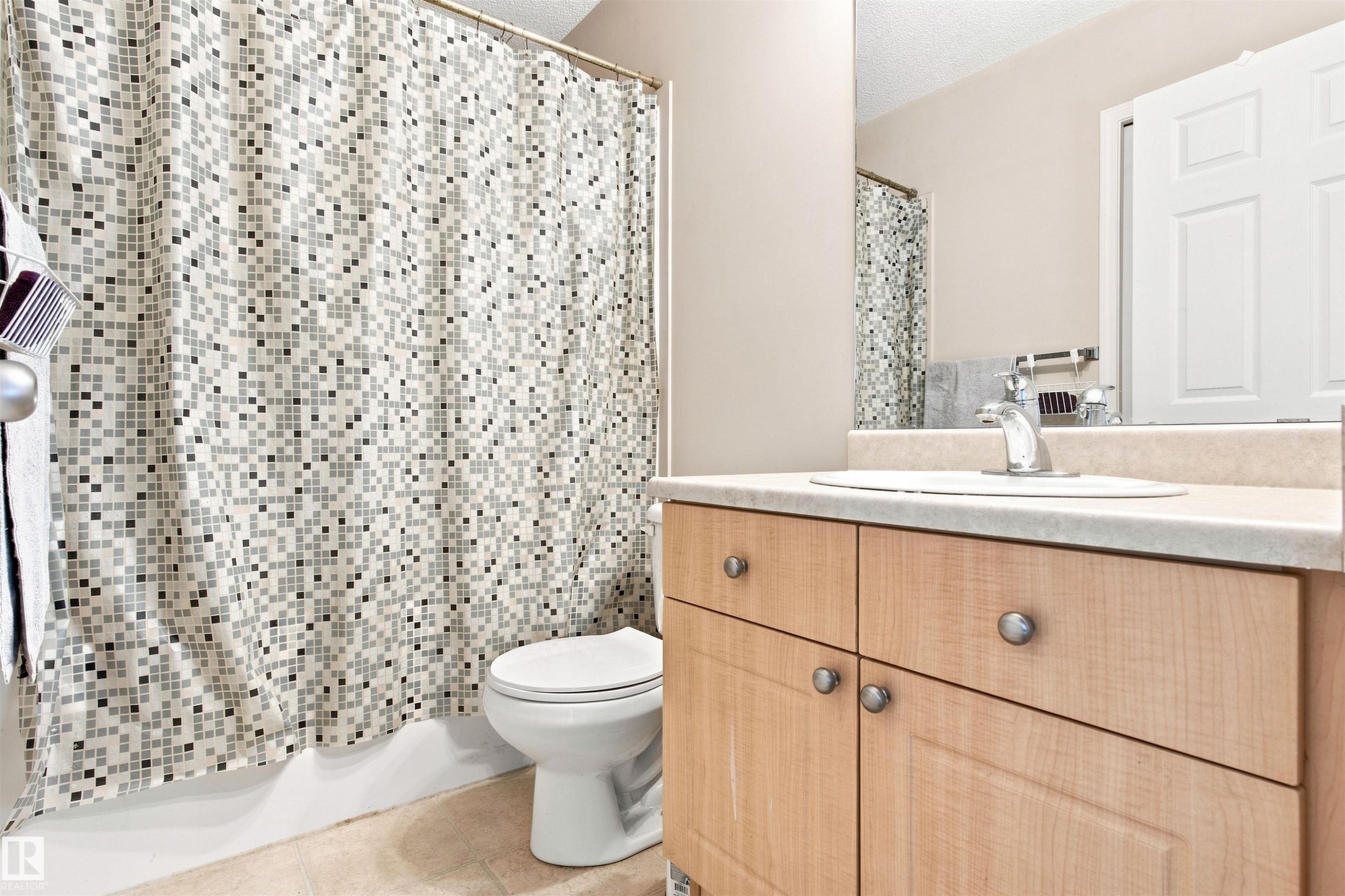 Light wood-finish vanity with a built-in sink, chrome faucet, and integrated mirror - 204 84 Street Sw, Edmonton, AB - Indoor Photo Showing Bathroom