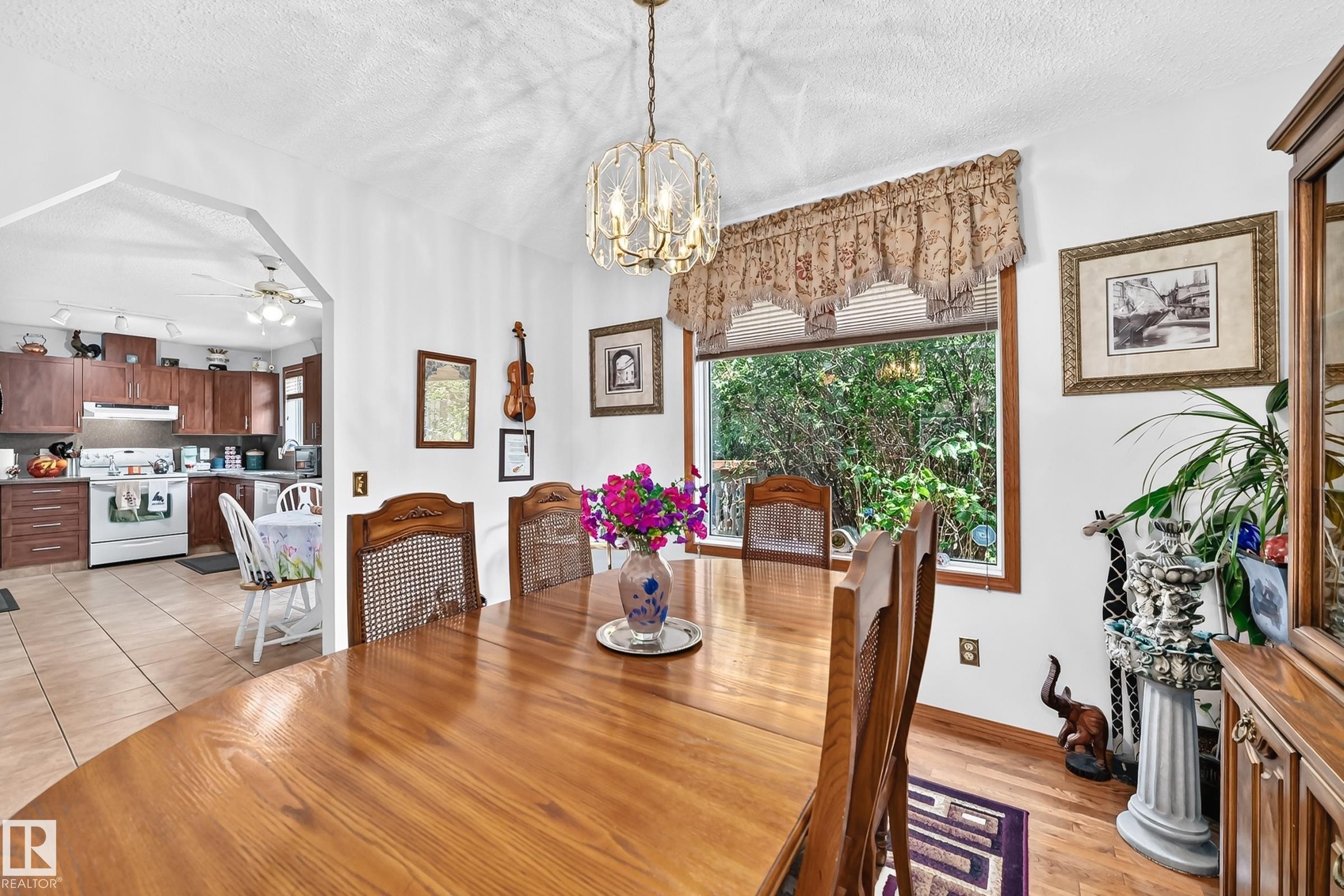 Dining area with wood-finish flooring, a large window, and an overhead decorative light fixture - 13069 37 Street Nw, Edmonton, AB - Indoor Photo Showing Dining Room