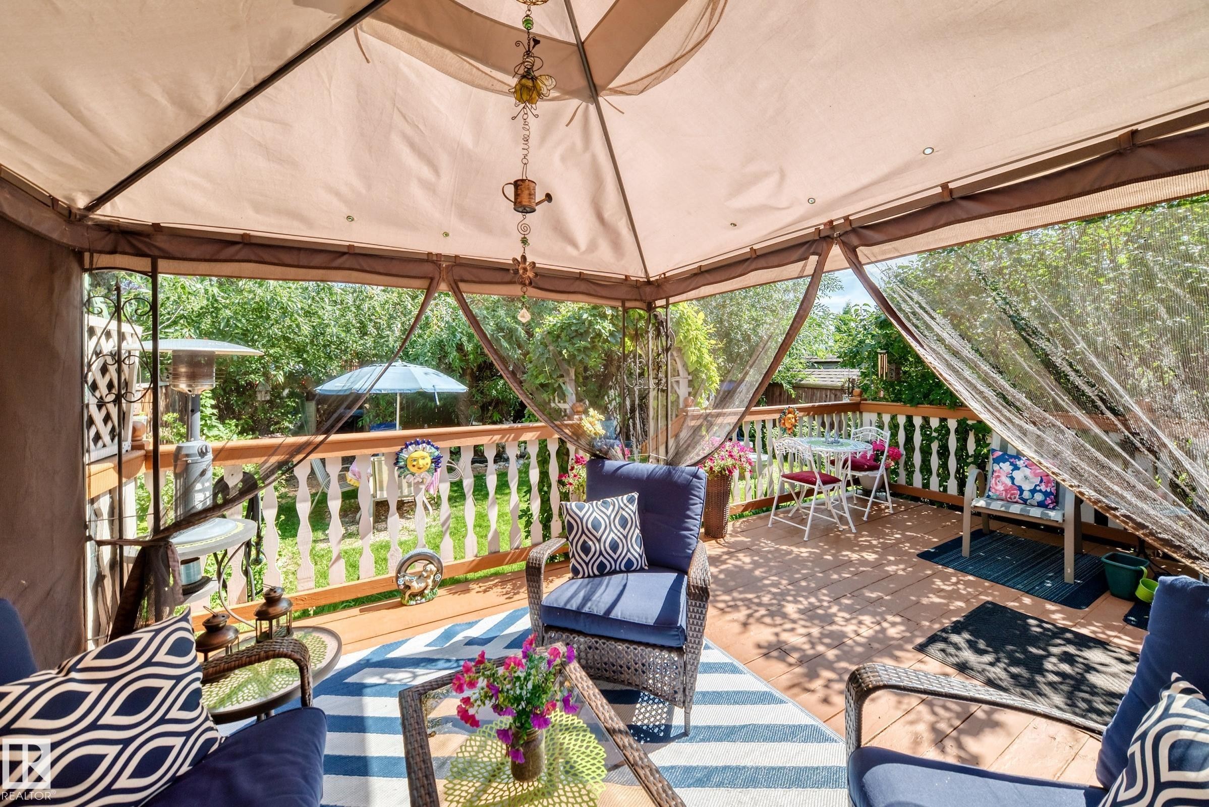 Covered outdoor patio with a full fabric canopy, wood-finish flooring, and white baluster railing - 13069 37 Street Nw, Edmonton, AB -
