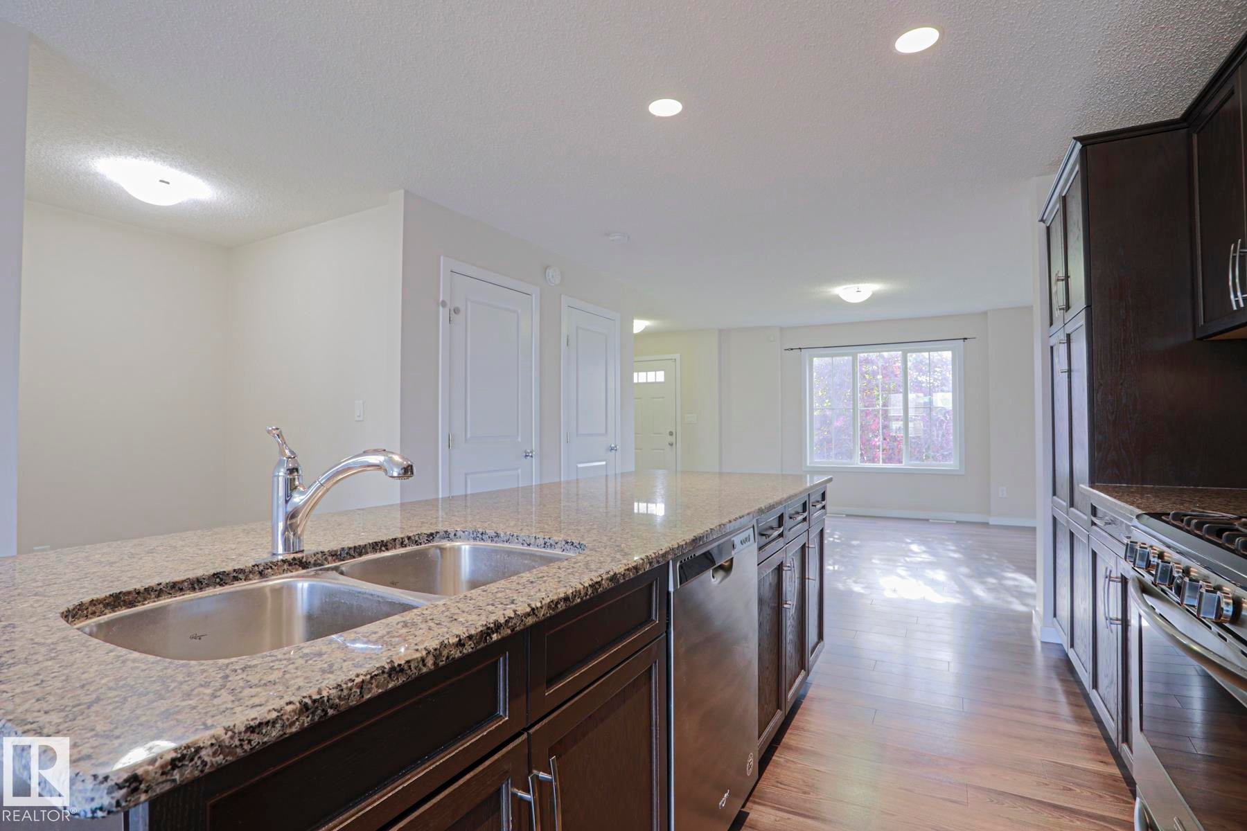 Kitchen island with a double stainless steel sink, granite countertop, and integrated dishwasher - 308 Watt Boulevard Sw, Edmonton, AB - Indoor Photo Showing Kitchen With Double Sink With Upgraded Kitchen