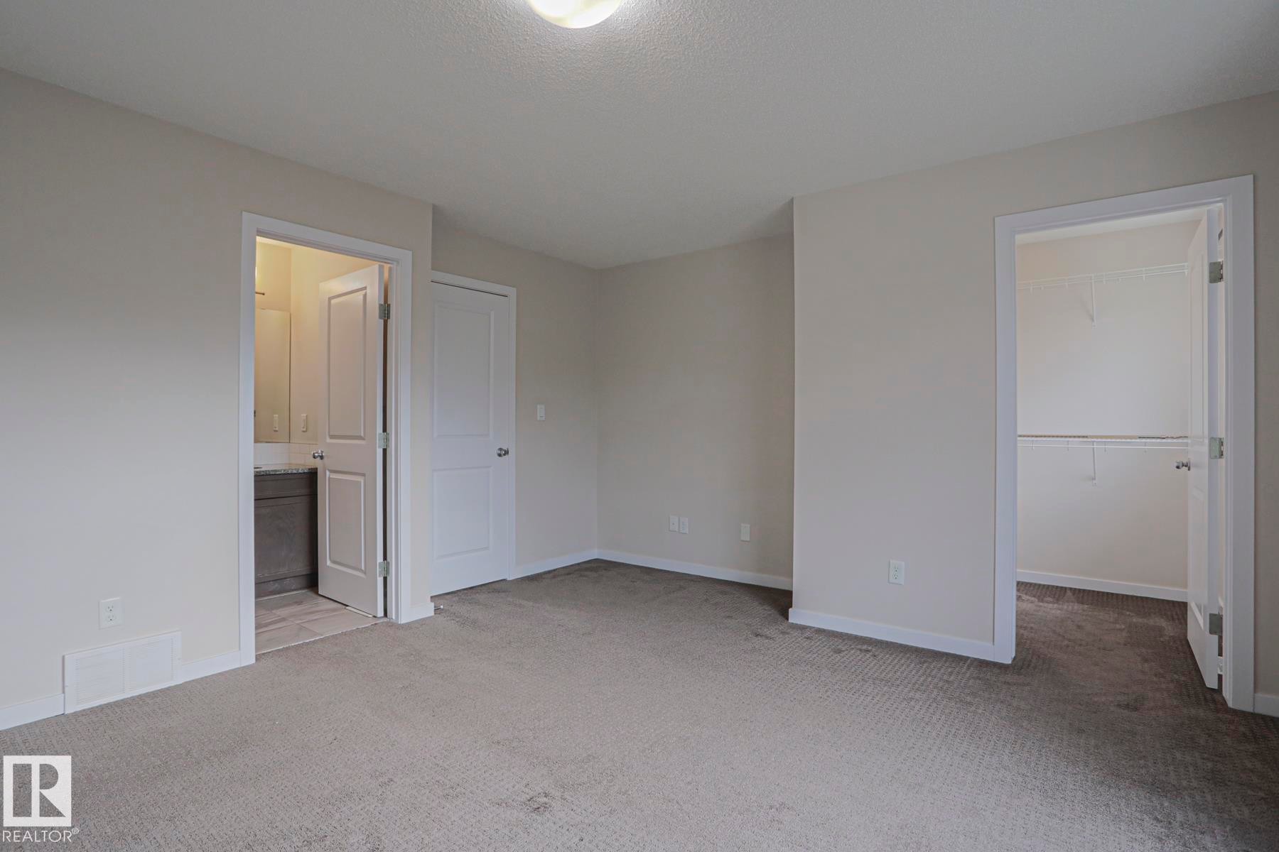 Plush carpet flooring, a walk-in closet with shelving, a bathroom with vanity, and a flush mount ceiling light - 308 Watt Boulevard Sw, Edmonton, AB - Indoor Photo Showing Other Room