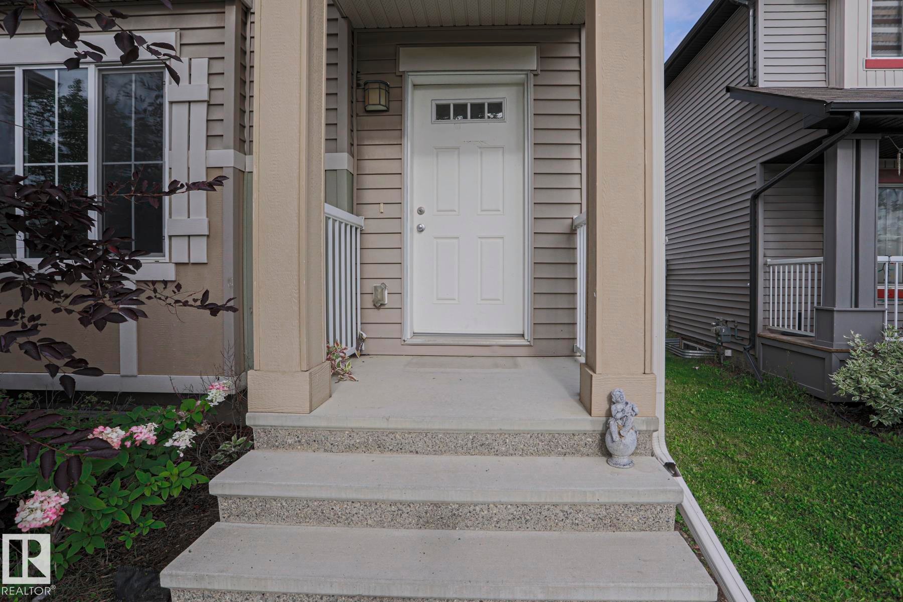 Entry with concrete stairs, white railing, and a paneled door featuring a window - 308 Watt Boulevard Sw, Edmonton, AB - Outdoor