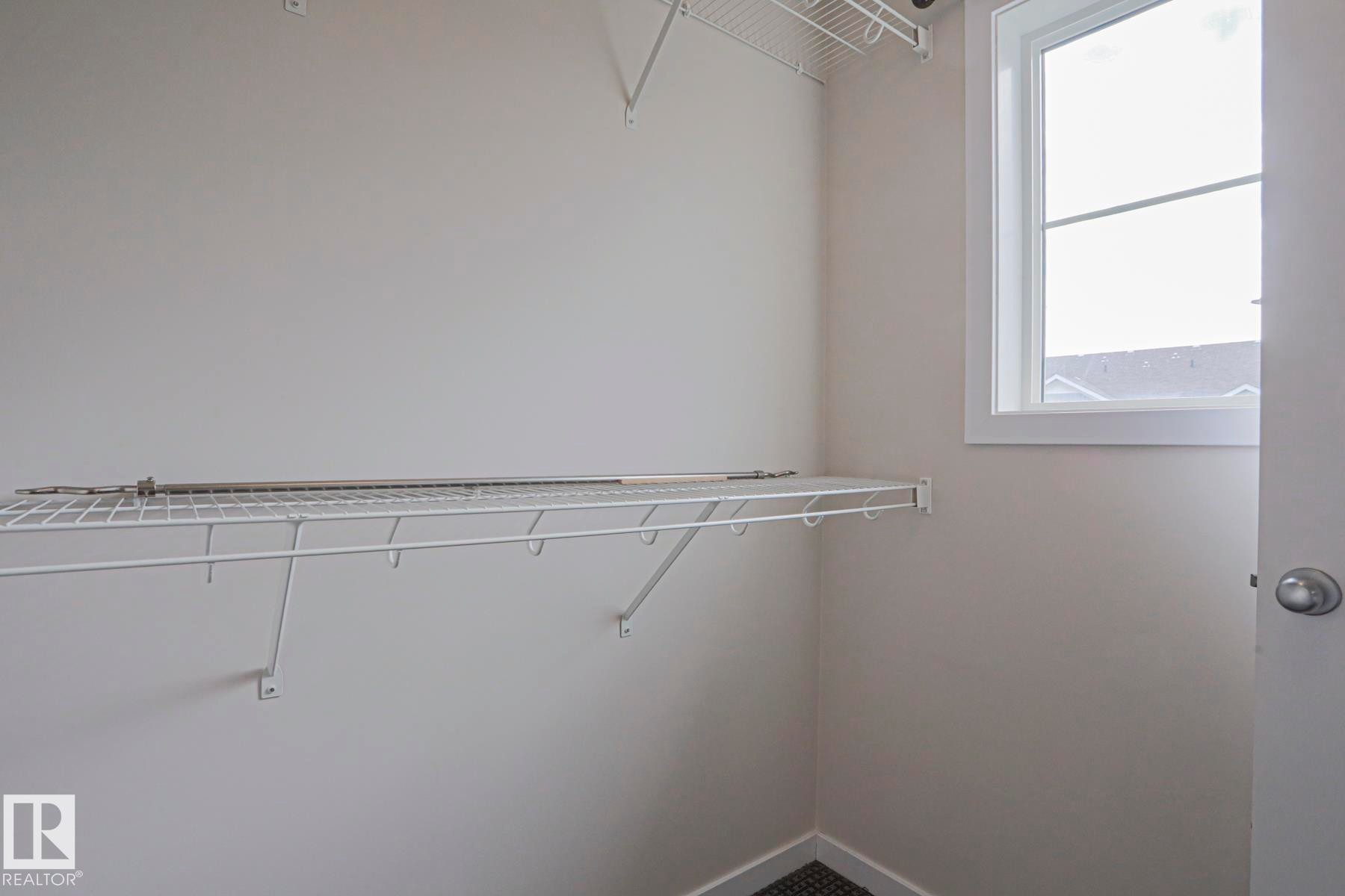 Built-in wire shelving, upper wire storage rack, bright window, and neutral wall tones - 308 Watt Boulevard Sw, Edmonton, AB - Indoor With Storage