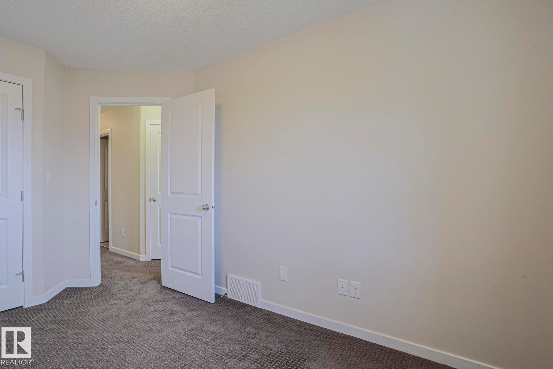 Neutral-toned wall finishes, textured carpet flooring, and white interior doors - 308 Watt Boulevard Sw, Edmonton, AB - Indoor Photo Showing Other Room