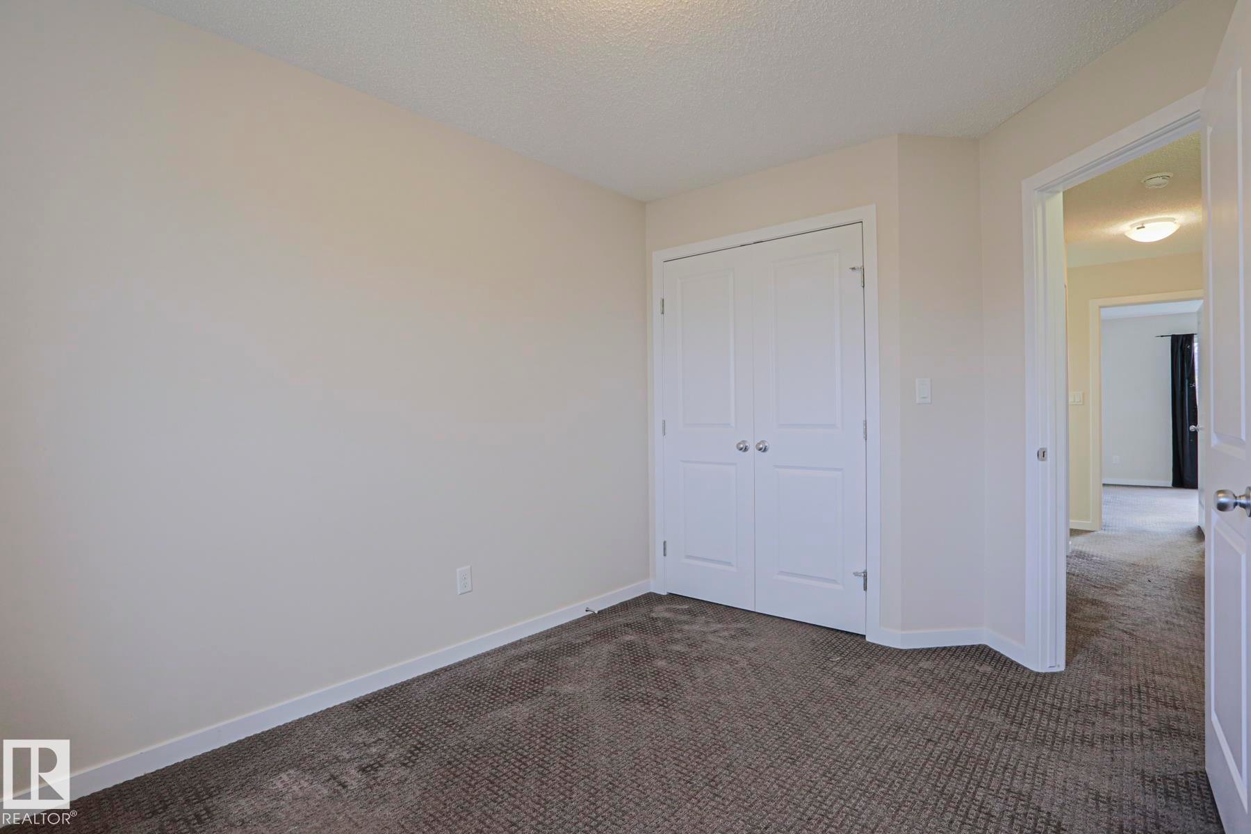 Neutral wall paint, built-in closet with panel doors, textured carpeting, and white trim - 308 Watt Boulevard Sw, Edmonton, AB - Indoor Photo Showing Other Room