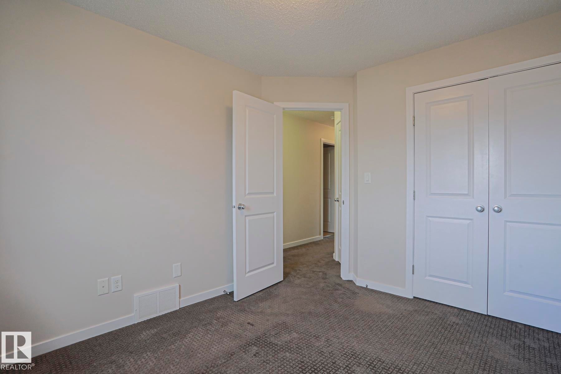 Neutral tone wall finish, textured ceiling, paneled door, bi-fold closet doors, and carpet flooring - 308 Watt Boulevard Sw, Edmonton, AB - Indoor Photo Showing Other Room