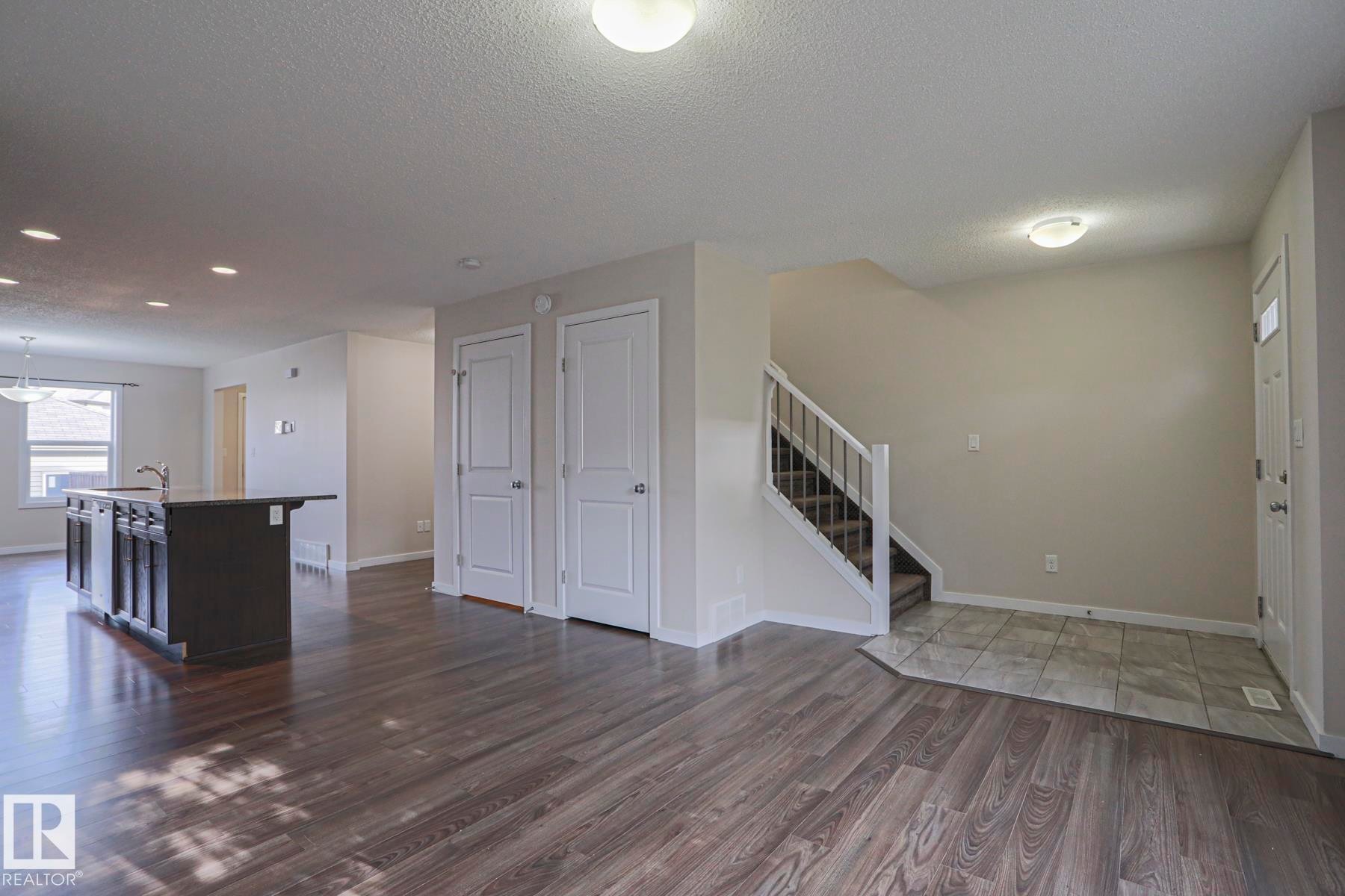 Open-concept living area featuring wood-finish flooring, recessed lighting, and a kitchen island with integrated sink - 308 Watt Boulevard Sw, Edmonton, AB - Indoor