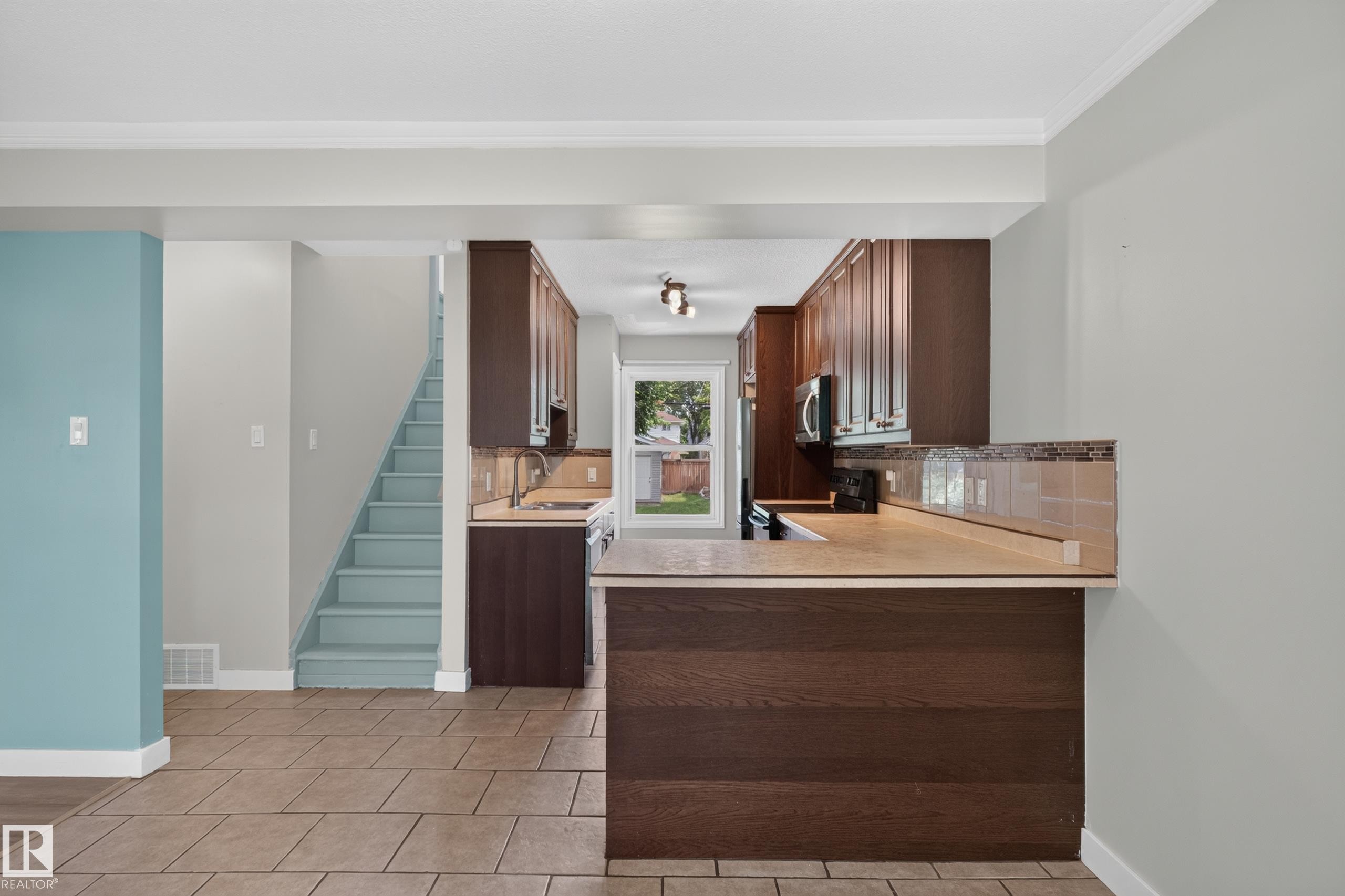 Kitchen featuring dark wood-finish cabinetry, stainless steel appliances, and a tiled backsplash - 11549 88 Street Nw, Edmonton, AB - Indoor Photo Showing Kitchen