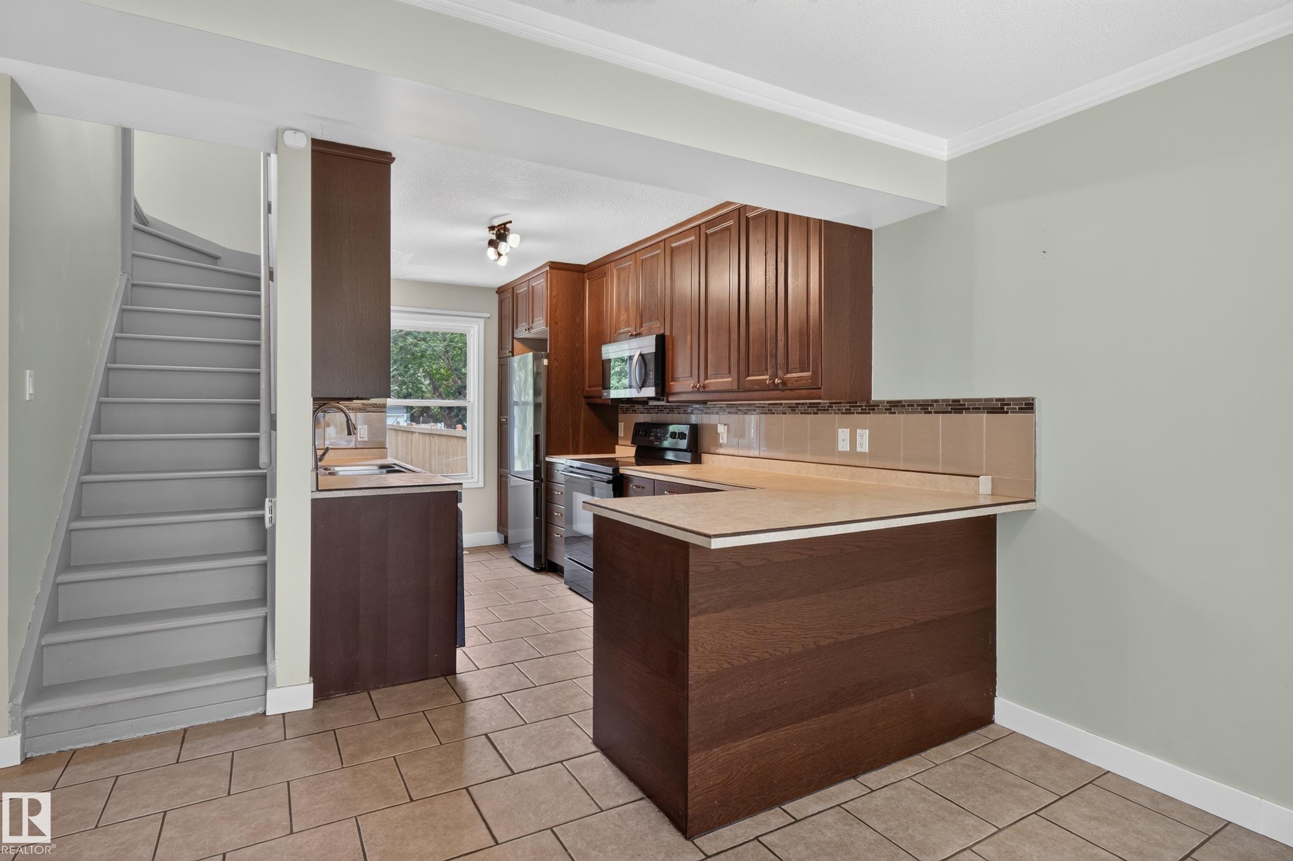 Kitchen with wood cabinetry, tiled flooring, and a breakfast bar - 11549 88 Street Nw, Edmonton, AB - Indoor Photo Showing Kitchen