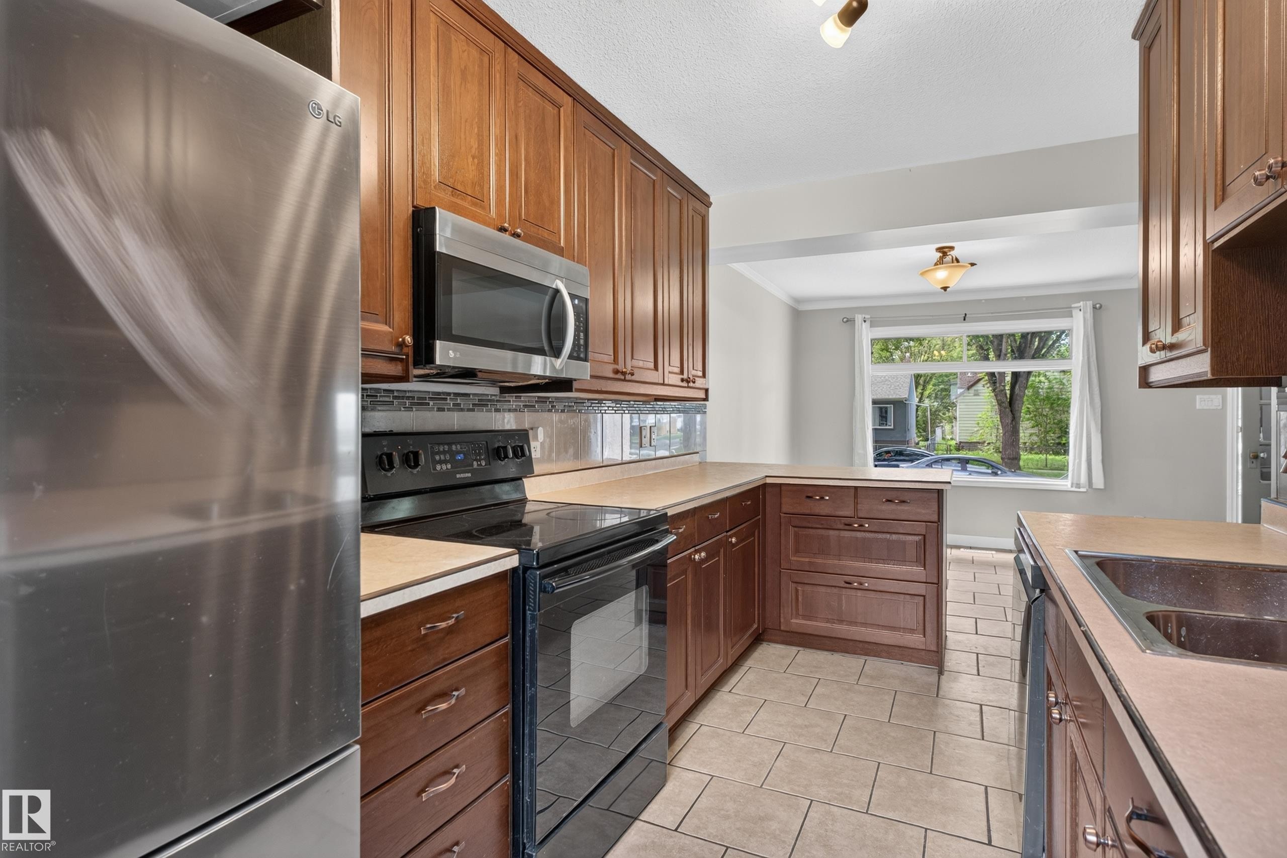 Kitchen featuring tile flooring, wood cabinetry, stainless steel appliances, and a window - 11549 88 Street Nw, Edmonton, AB - Indoor Photo Showing Kitchen With Double Sink